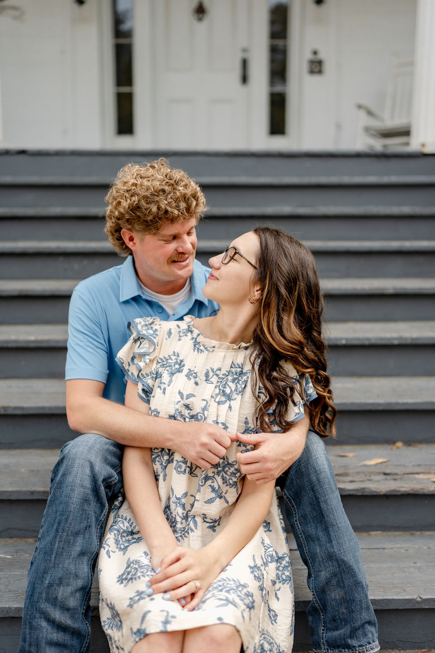 A couple shares an intimate moment while sitting on dark steps outdoors.