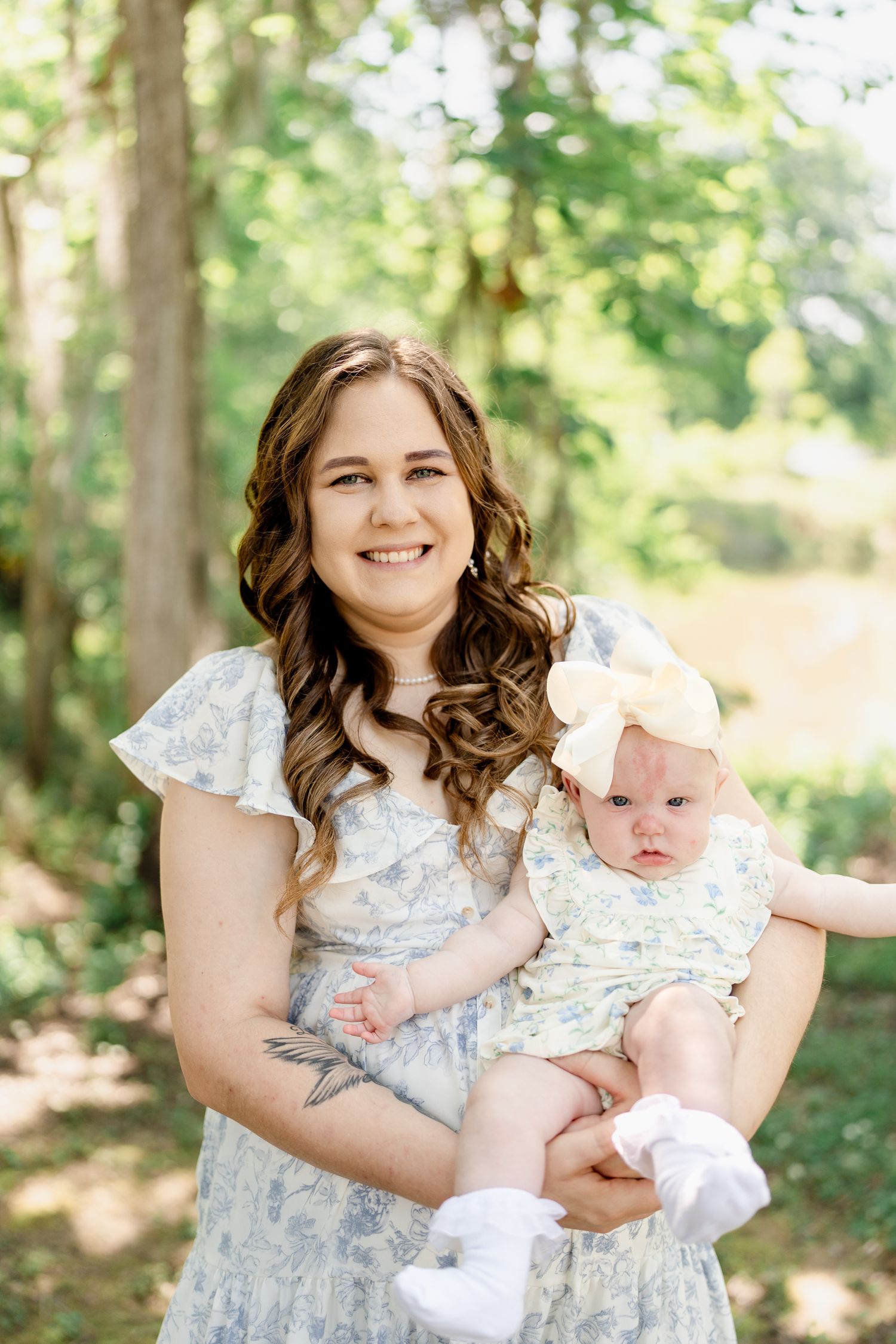 A tender moment captured between parent and baby in a sunlit forest setting.