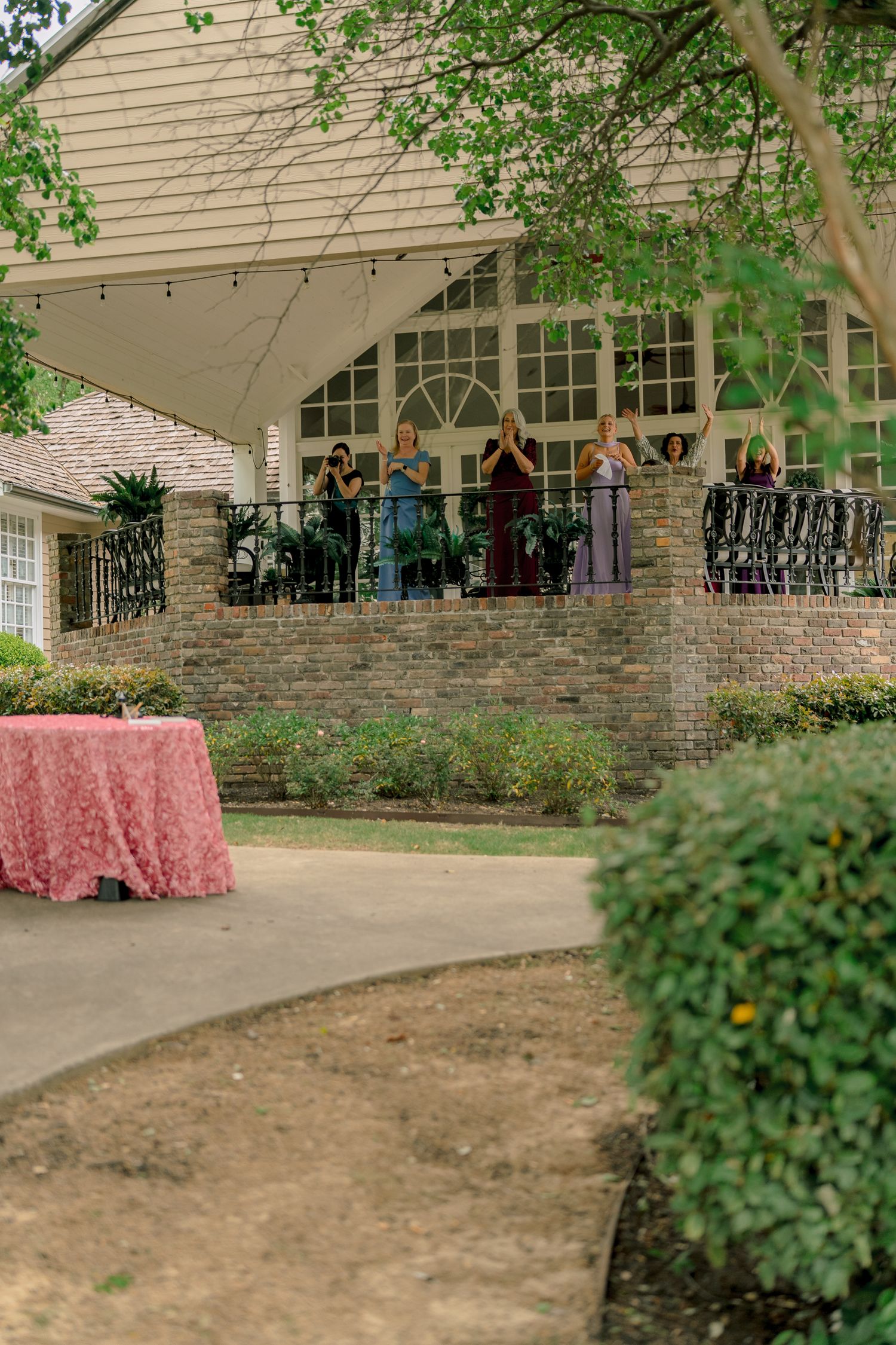 Guests gather on a brick terrace of an elegant venue with string lights during an outdoor wedding reception.