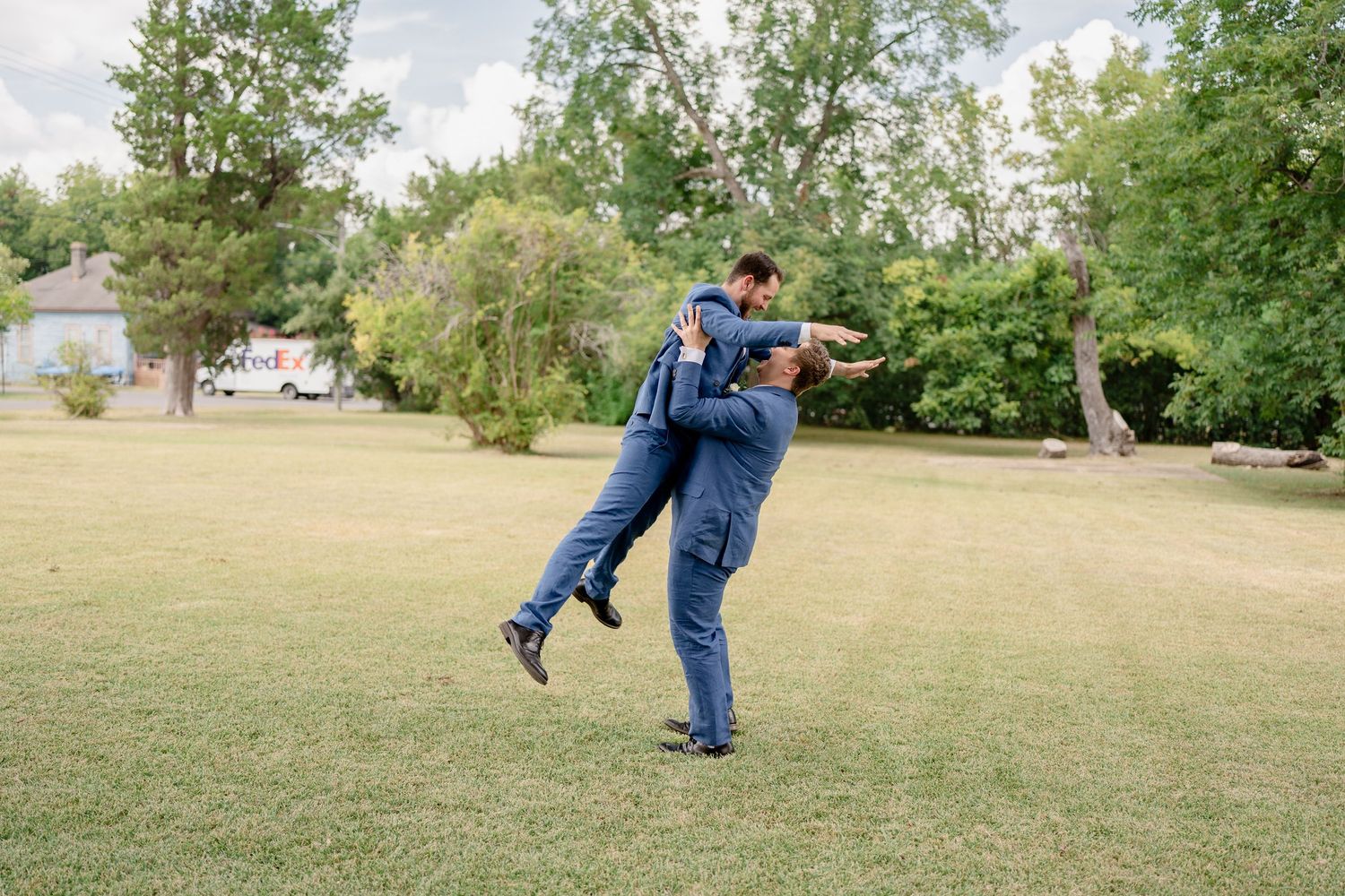 A person in blue jeans practices martial arts moves in a grassy park on a sunny day.