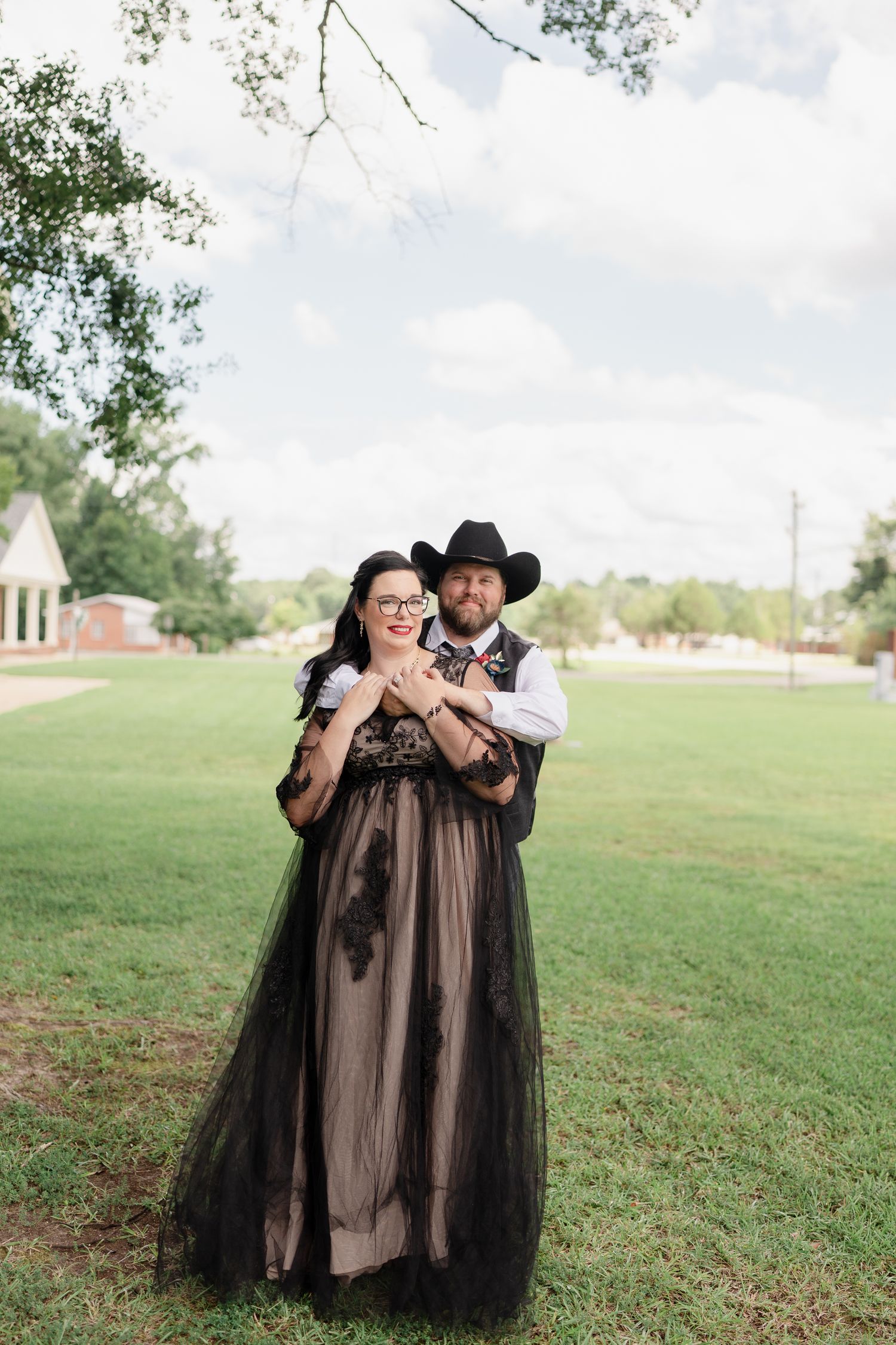 A romantic photo sequence on a grassy hillside featuring a flowing black tulle dress and cowboy hat.