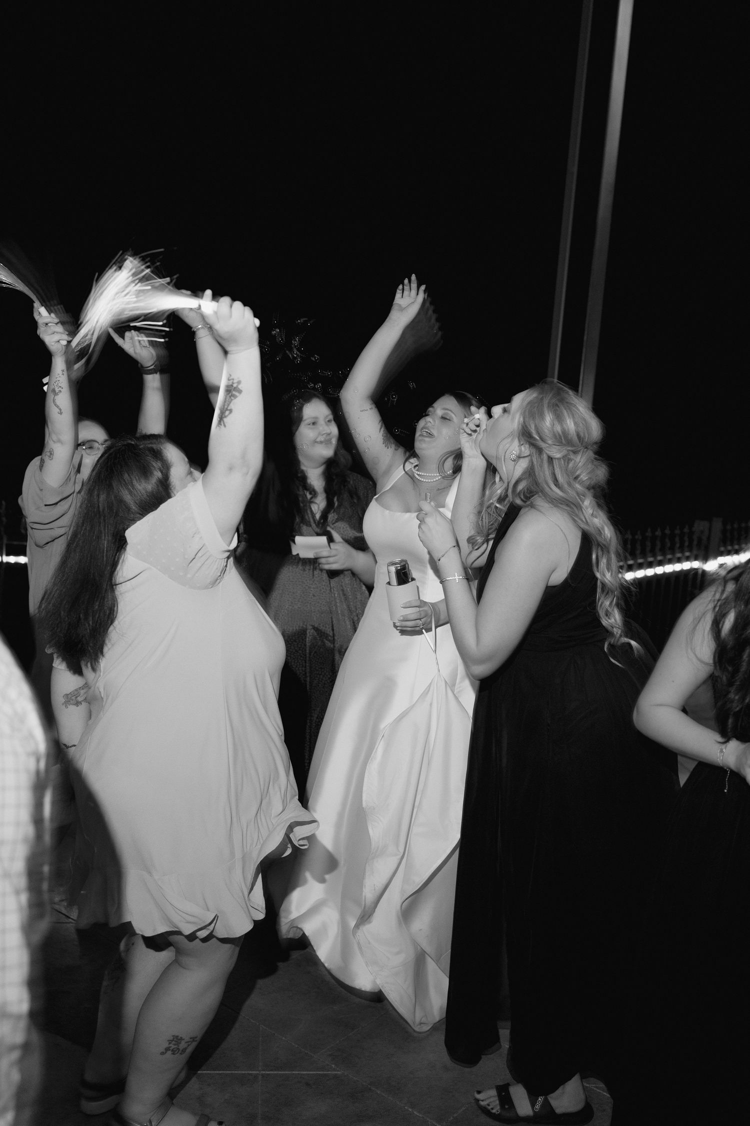 Wedding guests dancing and celebrating on the dance floor at a nighttime reception.