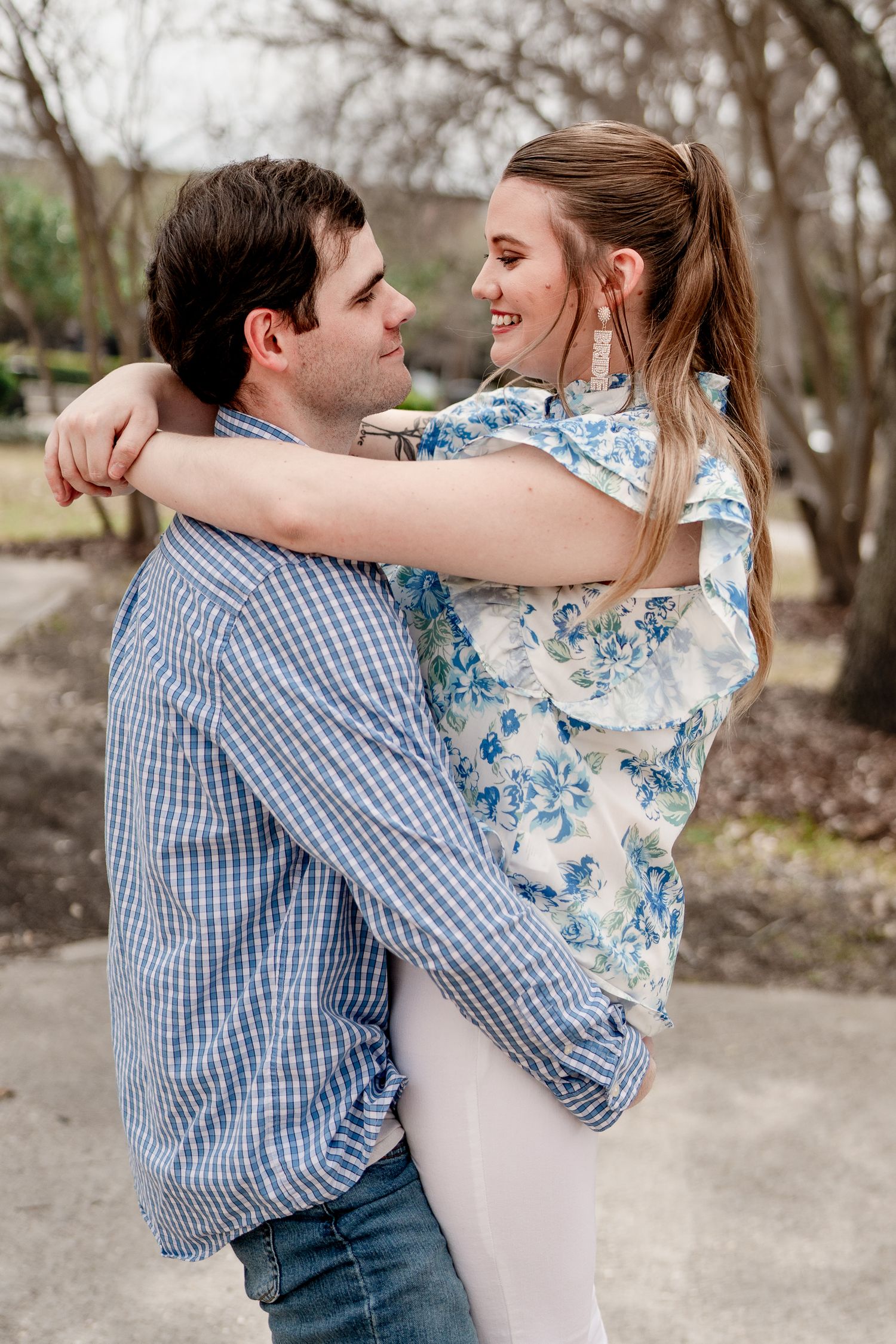 Playful couple embraces and spins around outdoors in coordinated casual attire.