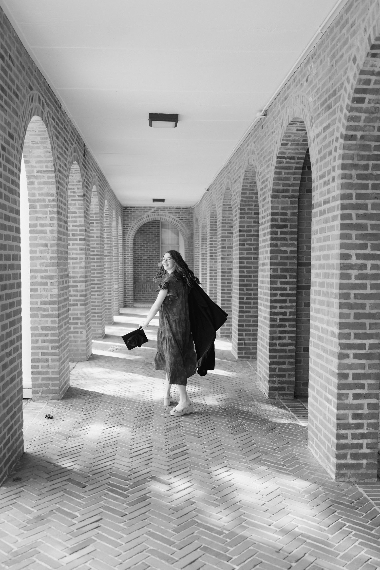 Black and white photos of a brick archway corridor with someone walking through it.