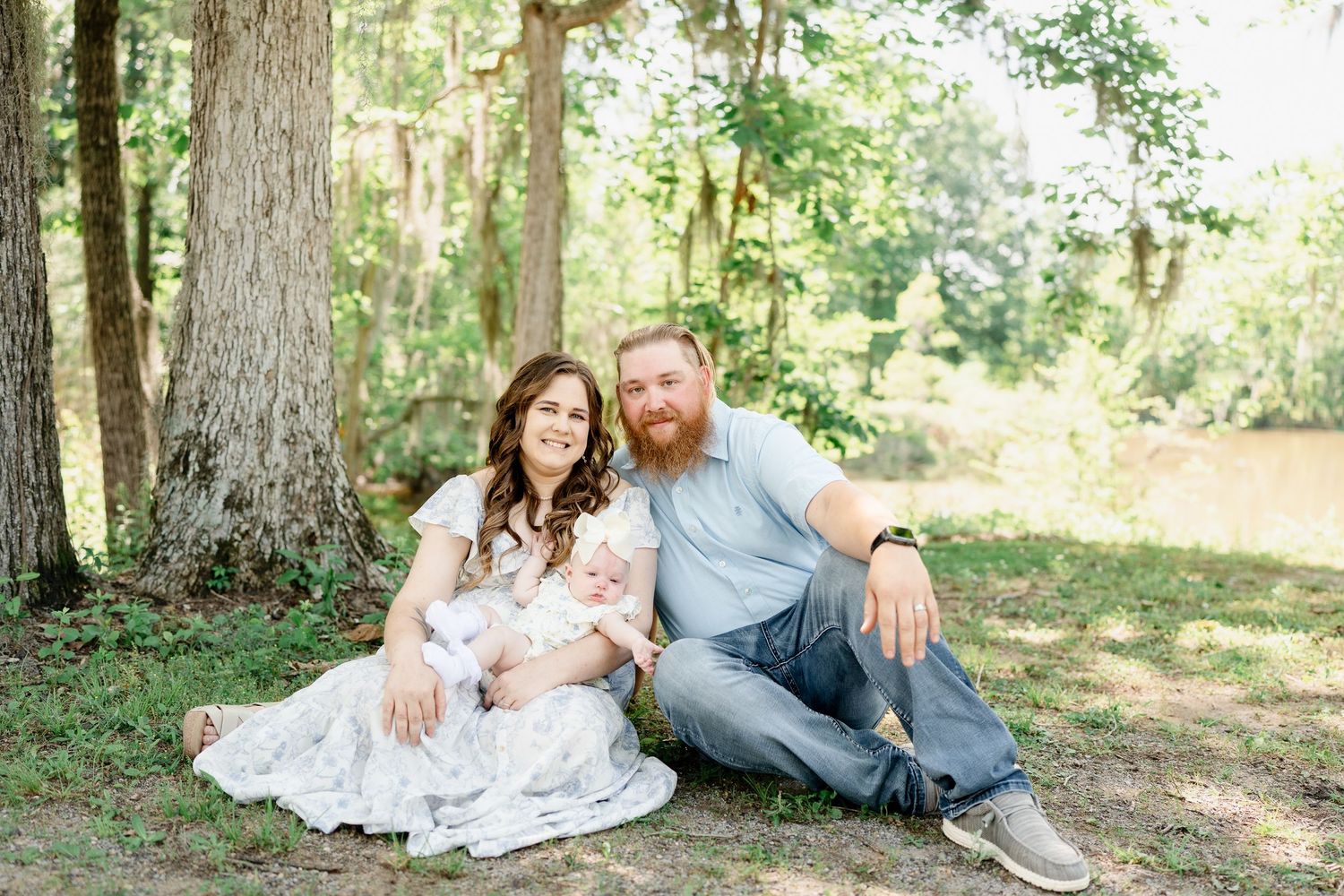 Couple shares intimate moments in a sunlit forest setting wearing coordinated casual outfits.