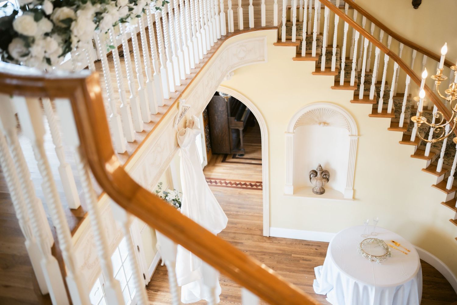 Elegant curved staircase with white spindles and wooden handrail in a luxury wedding venue interior.