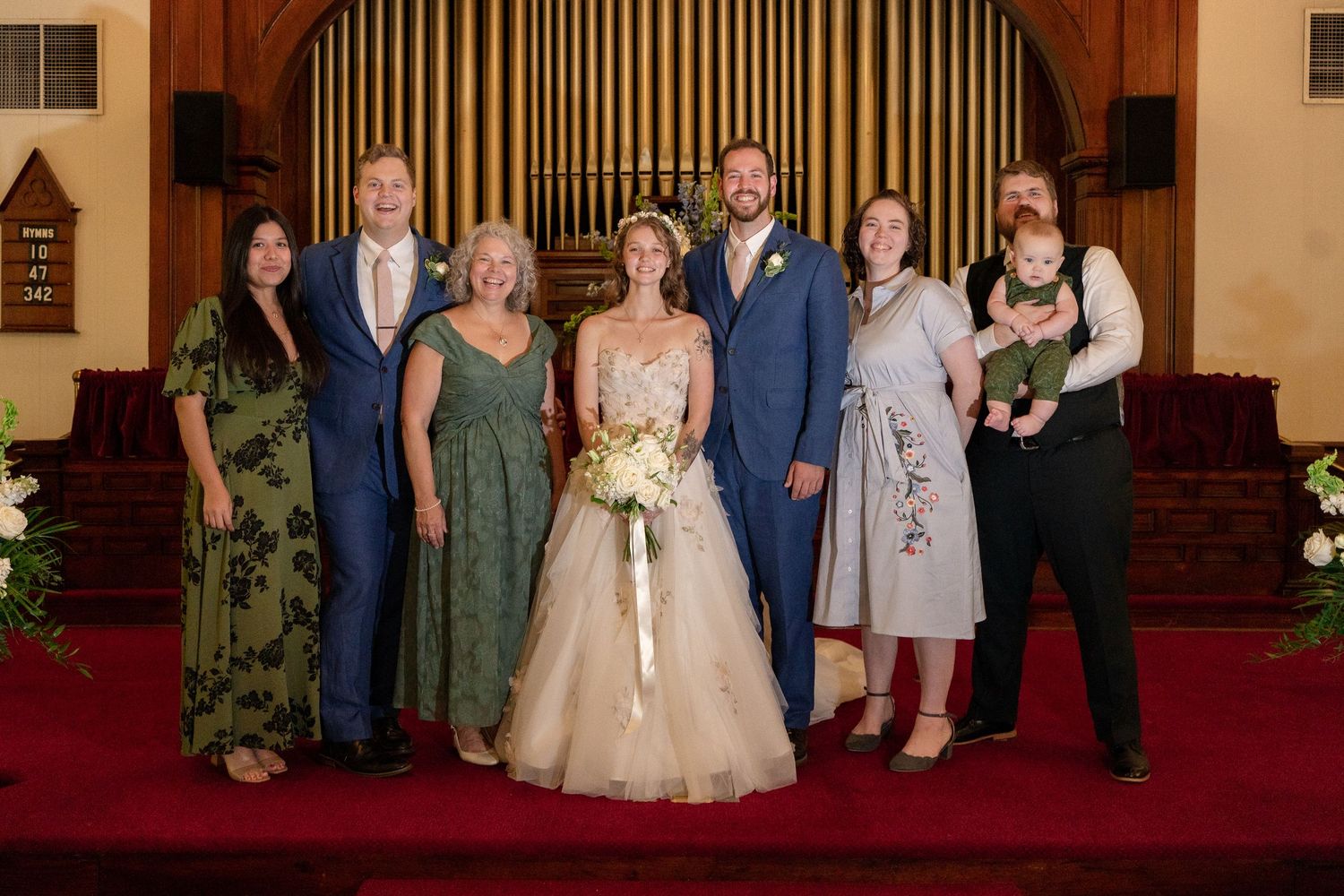 Wedding party poses for formal portraits inside a traditional church sanctuary with brick walls and wooden details.