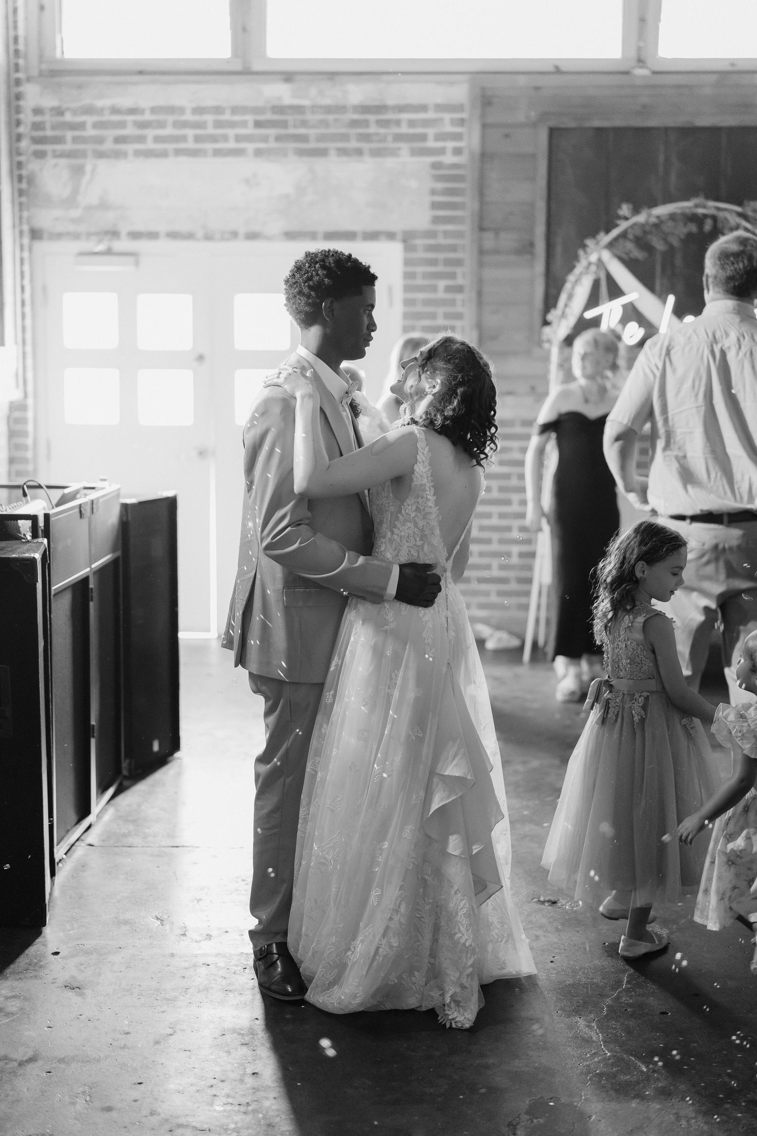 Black and white photo of a bride and groom sharing their first dance at a wedding reception.
