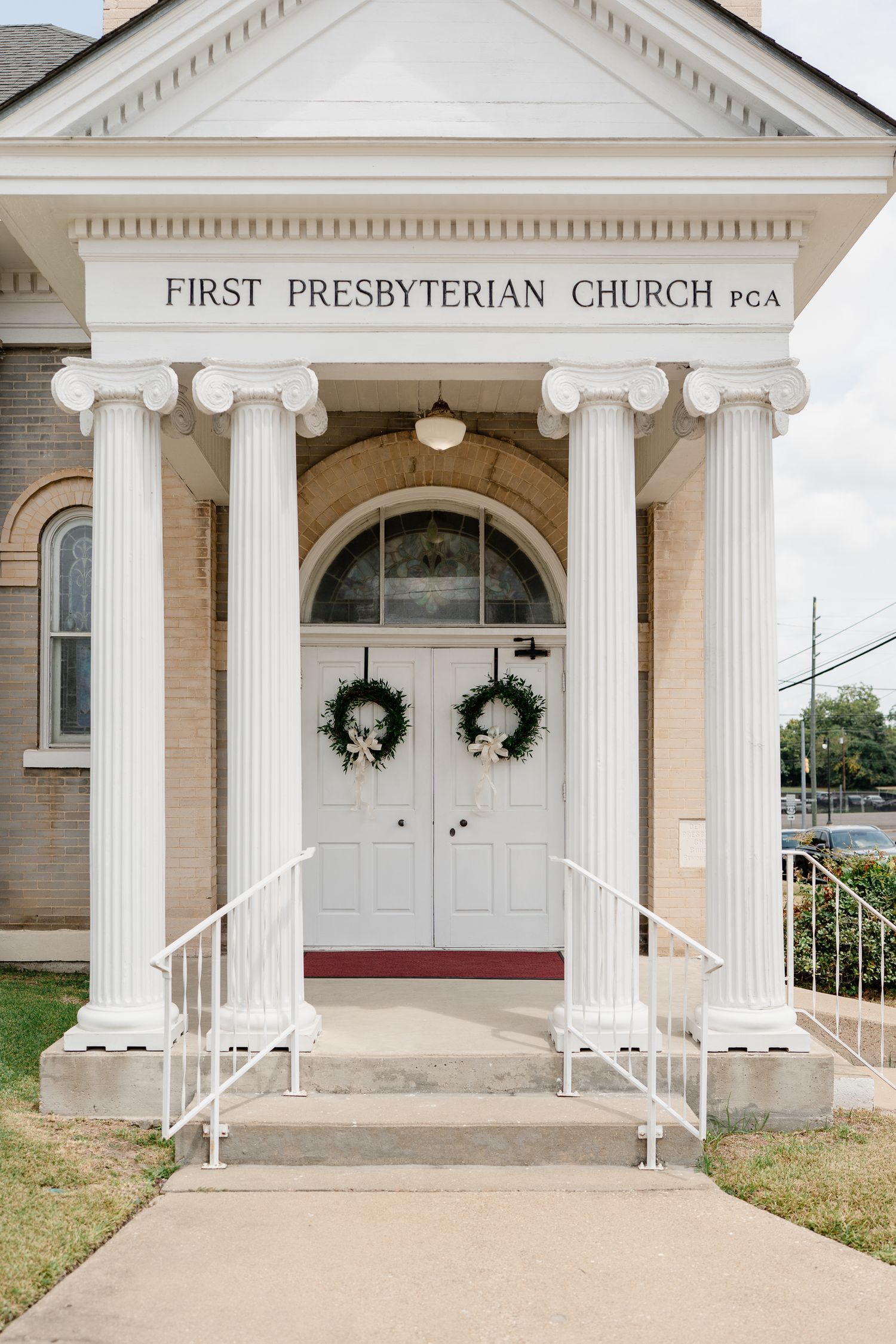 Classic white Presbyterian church entrance with columns, double doors, and matching wreaths.