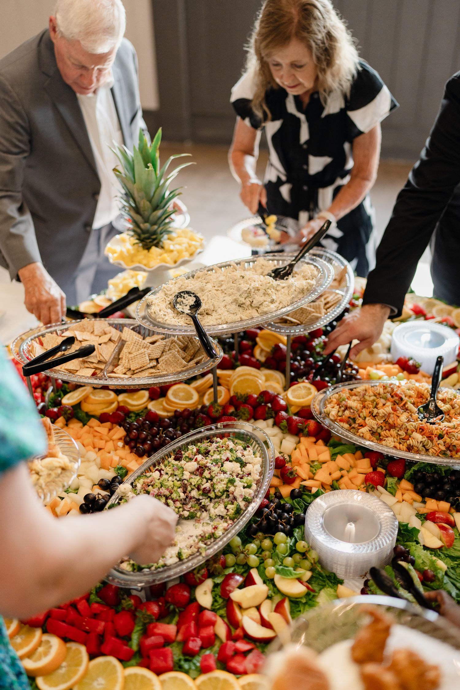 Elegant wedding reception buffet spread with fresh fruits, vegetables, and appetizers arranged on decorated tables.