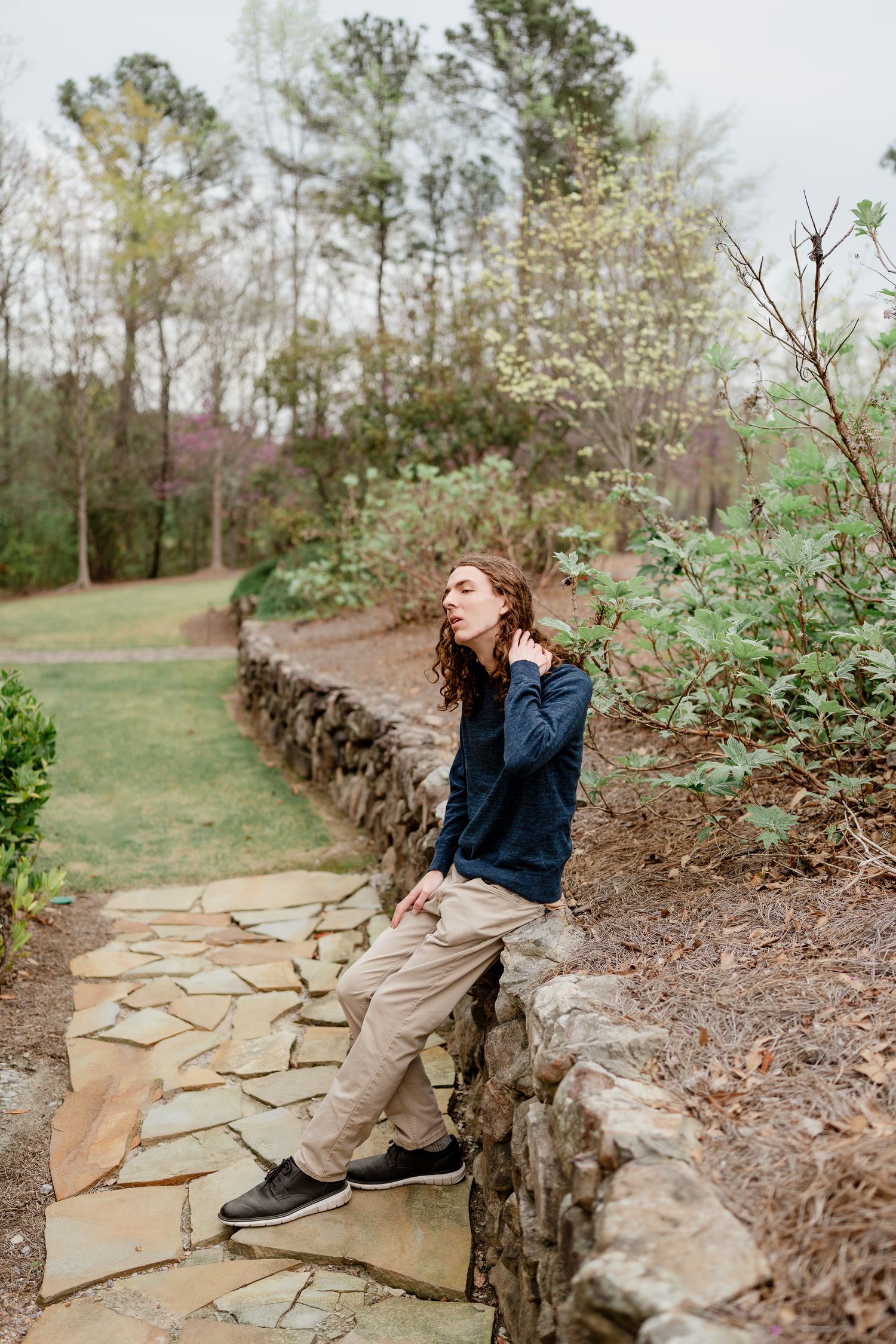 Stone pathway with natural rock wall meanders through serene garden setting.