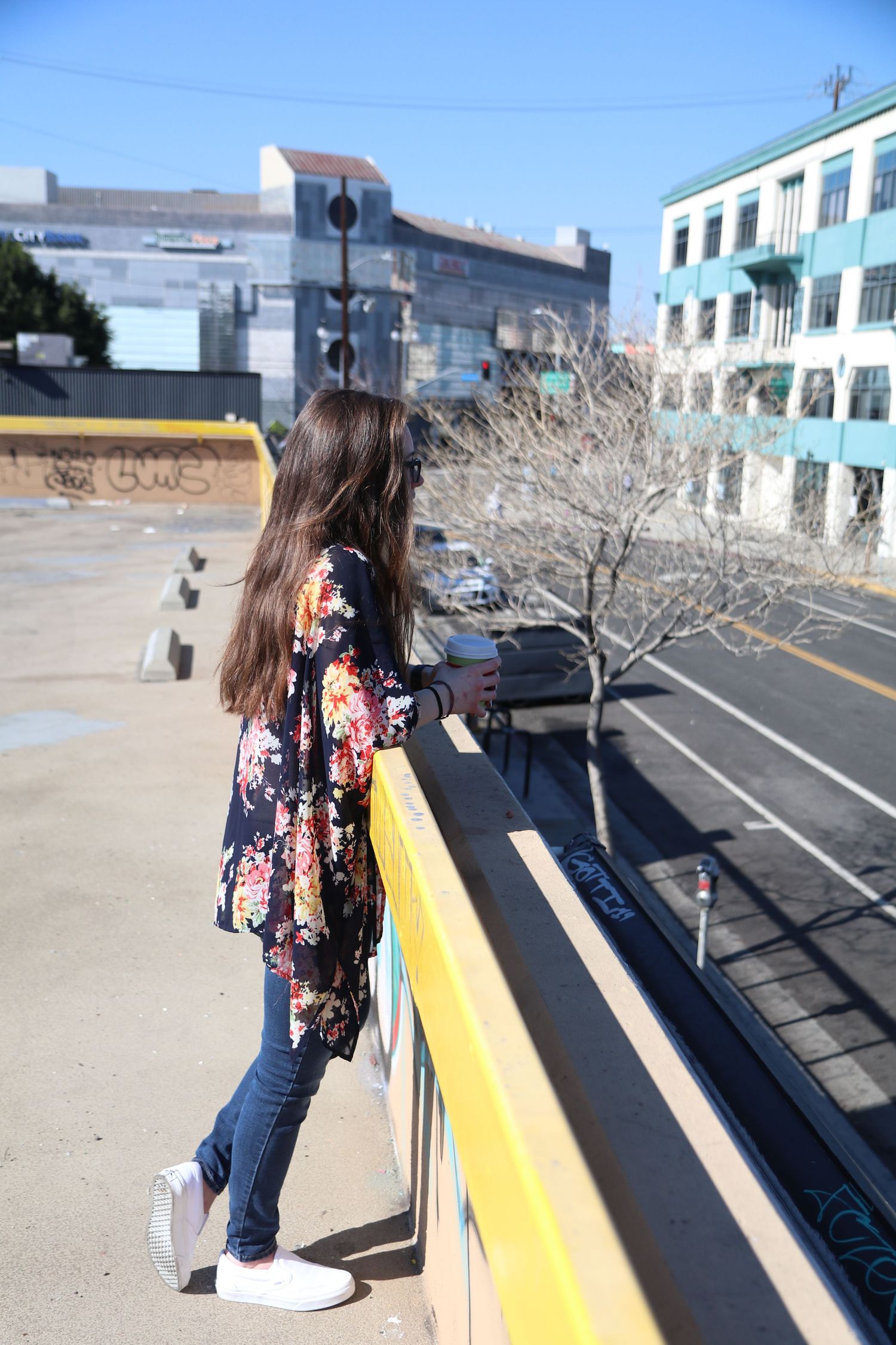 Urban fashion photo showing floral kimono and jeans while overlooking a city street.