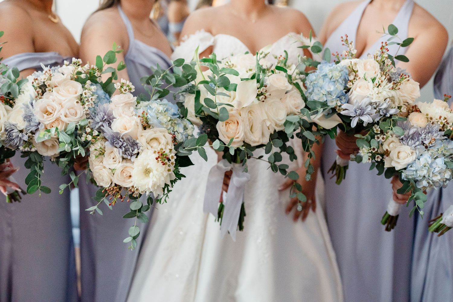 Elegant wedding bouquets featuring white roses, blue hydrangeas and greenery.
