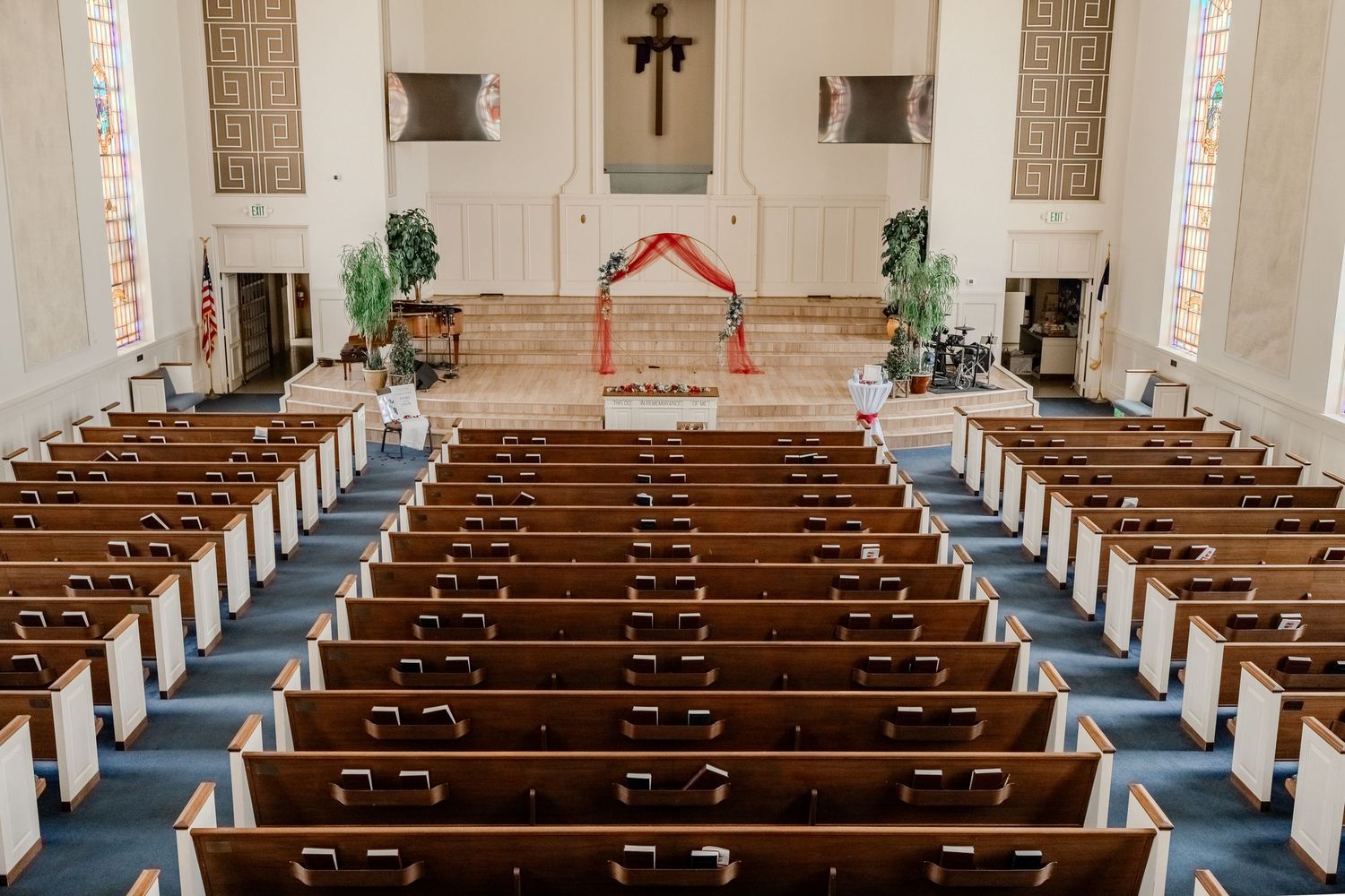 Interior view of an empty church sanctuary with wooden pews and stained glass windows.