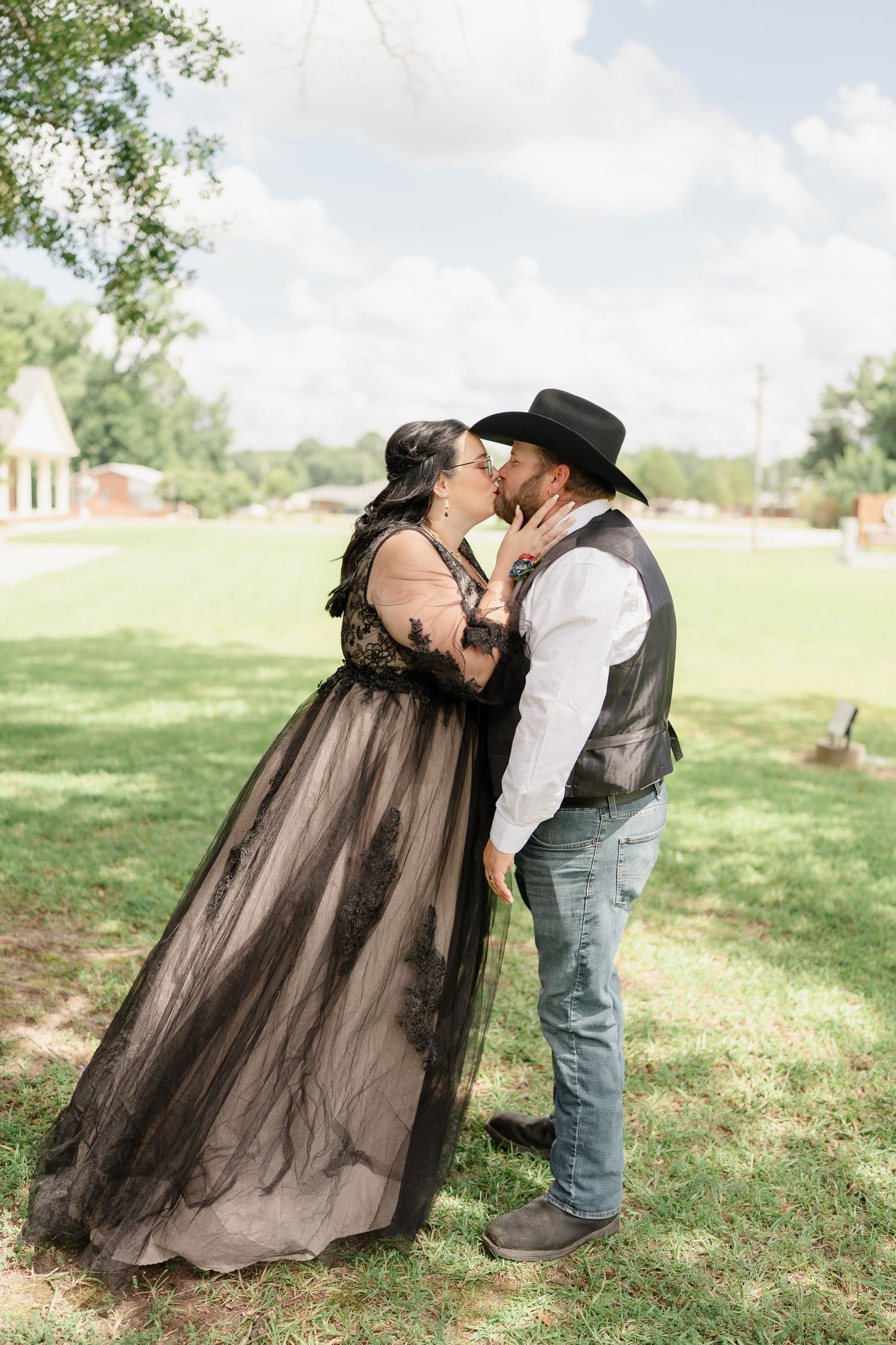 Romantic sequence shows couple in black dress and western wear embracing on grassy hillside.