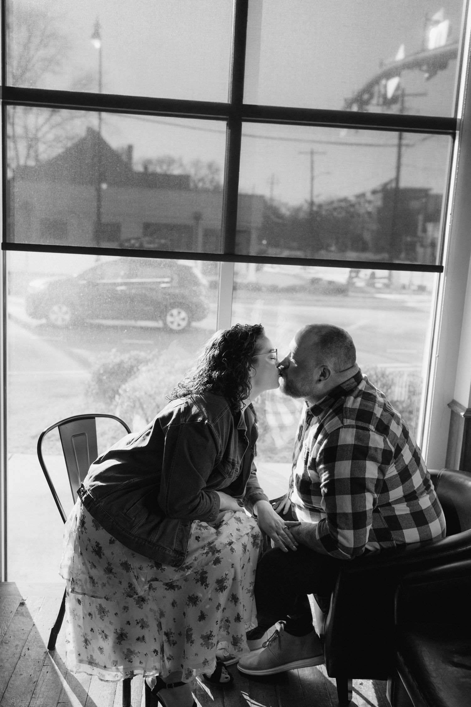 A silhouetted couple sitting by large windows in a casual indoor setting.
