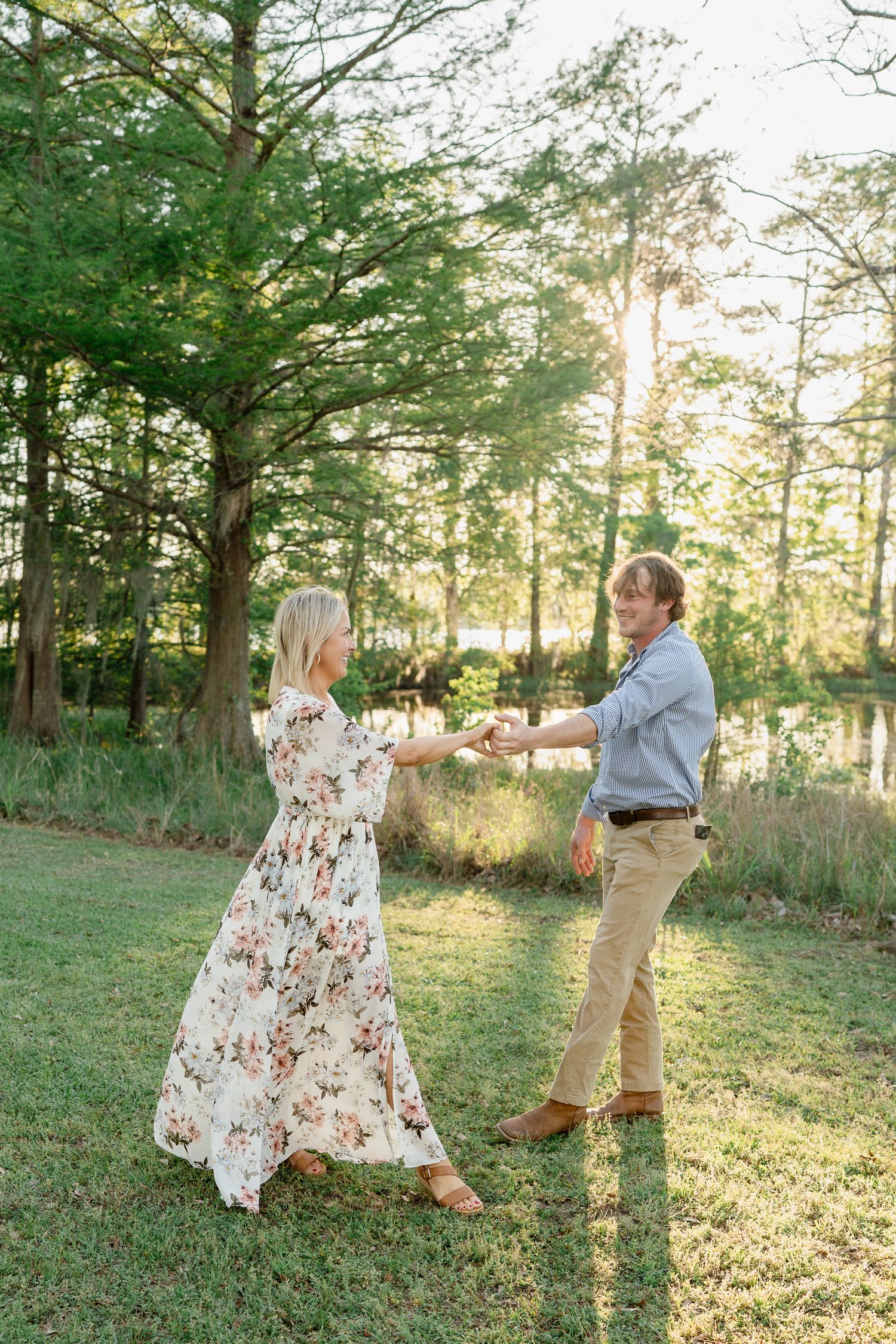 A couple dances playfully in a sunlit forest clearing.