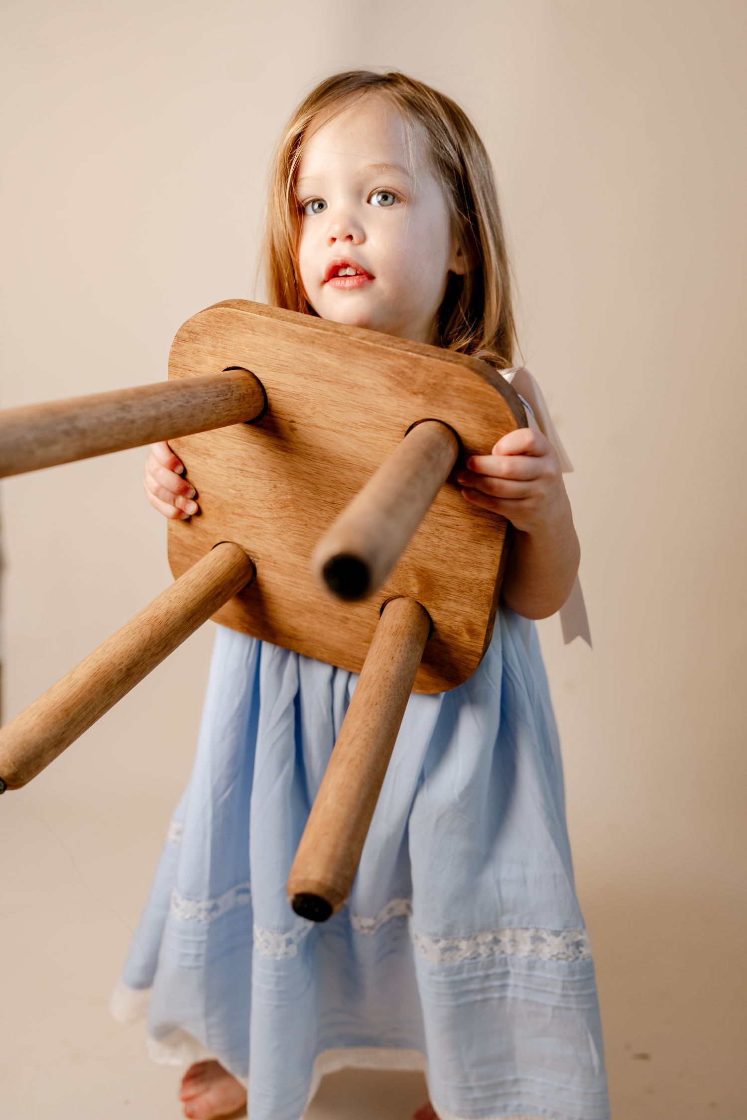 A wooden toy horse is displayed against a light studio background with blue dress details.
