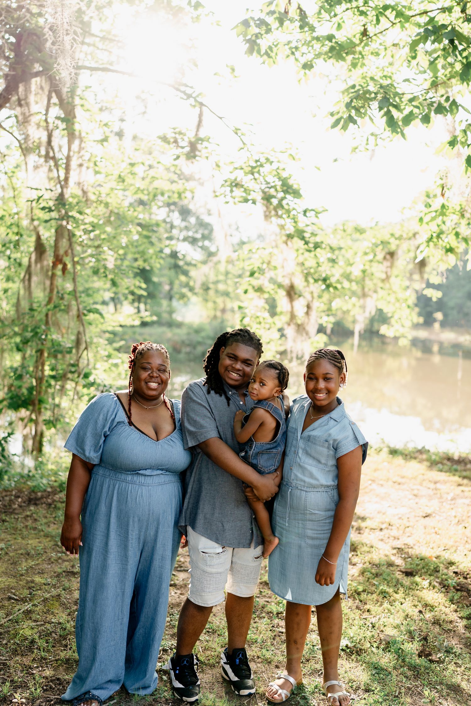A joyful family in coordinating blue outfits shares laughs during an outdoor photo session.