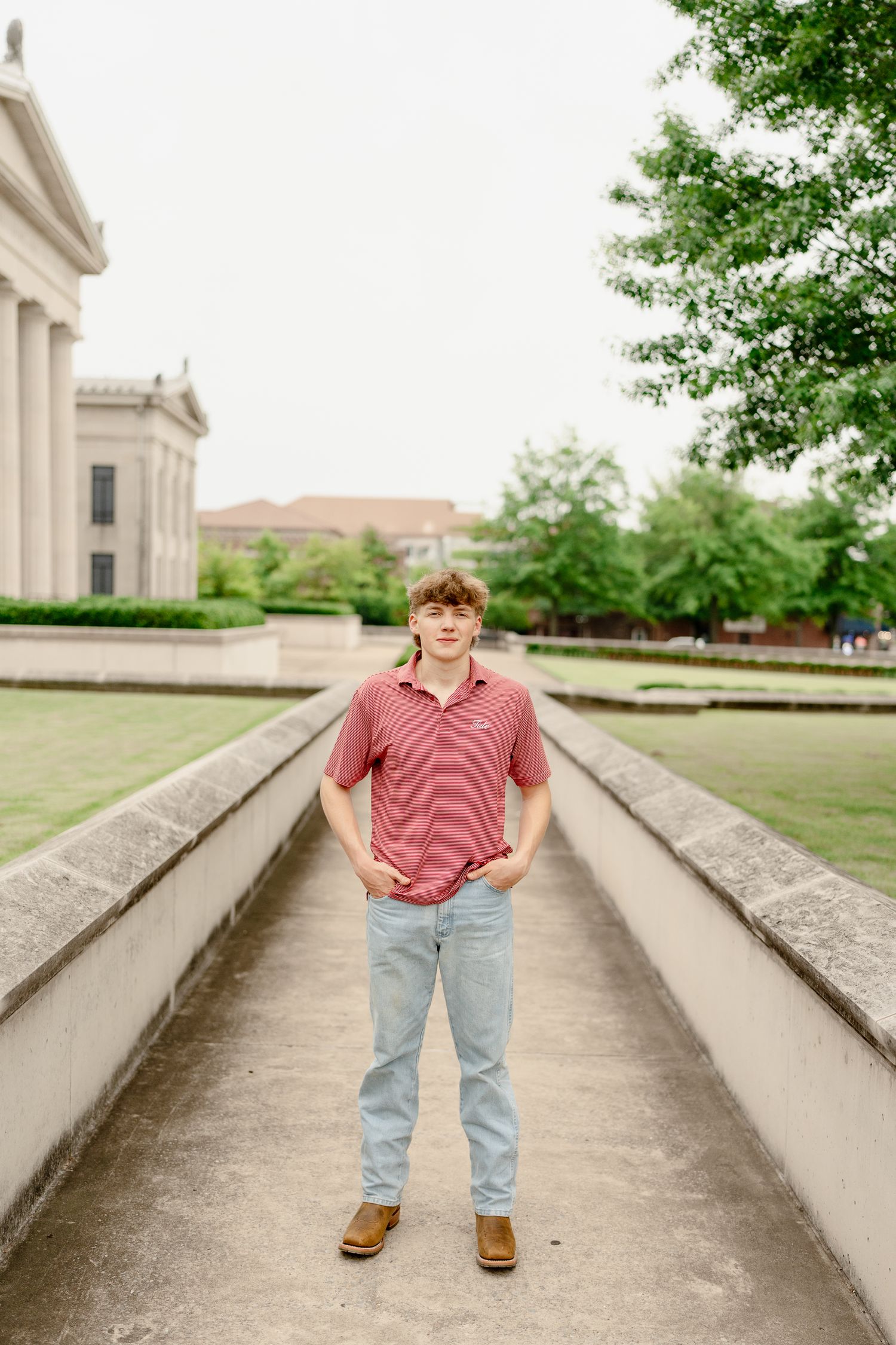 A casual portrait in front of a classical building with stone columns and walkway.