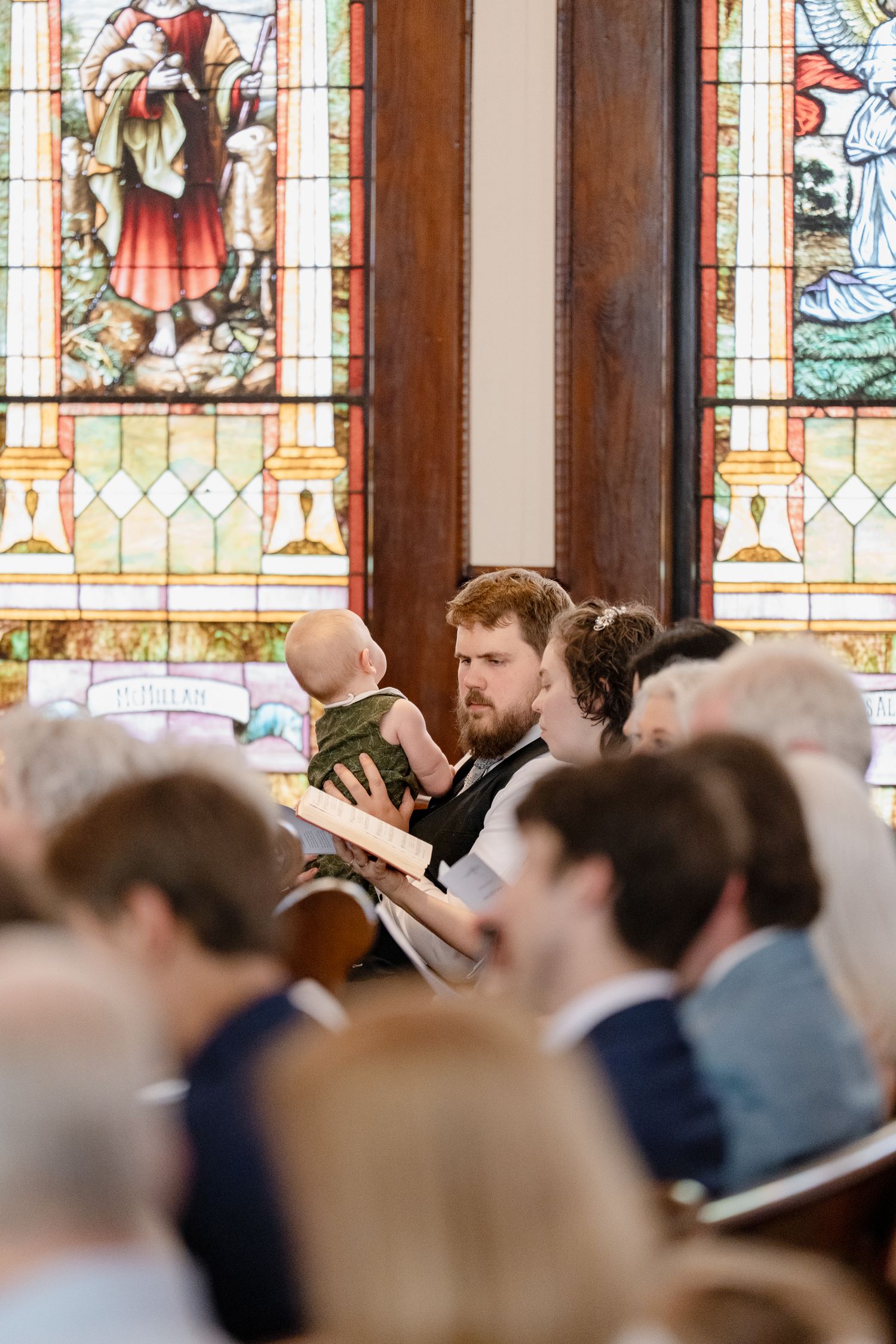 Stained glass windows line the walls of a traditional church sanctuary during a service.