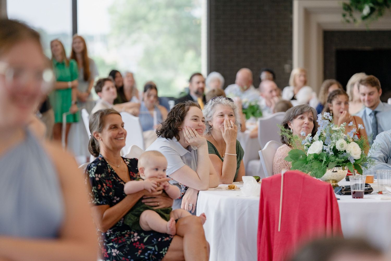 Wedding reception guests enjoy conversation and laughter at decorated tables with pink accents.