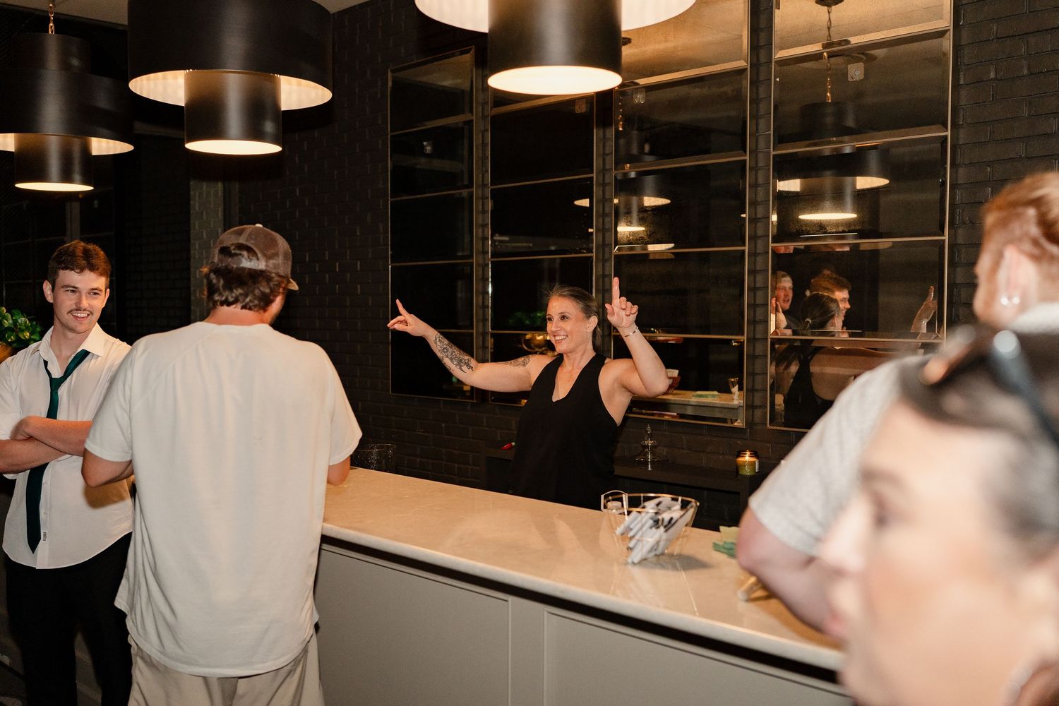 Guests interact at a modern bar area with pendant lighting during an evening event.