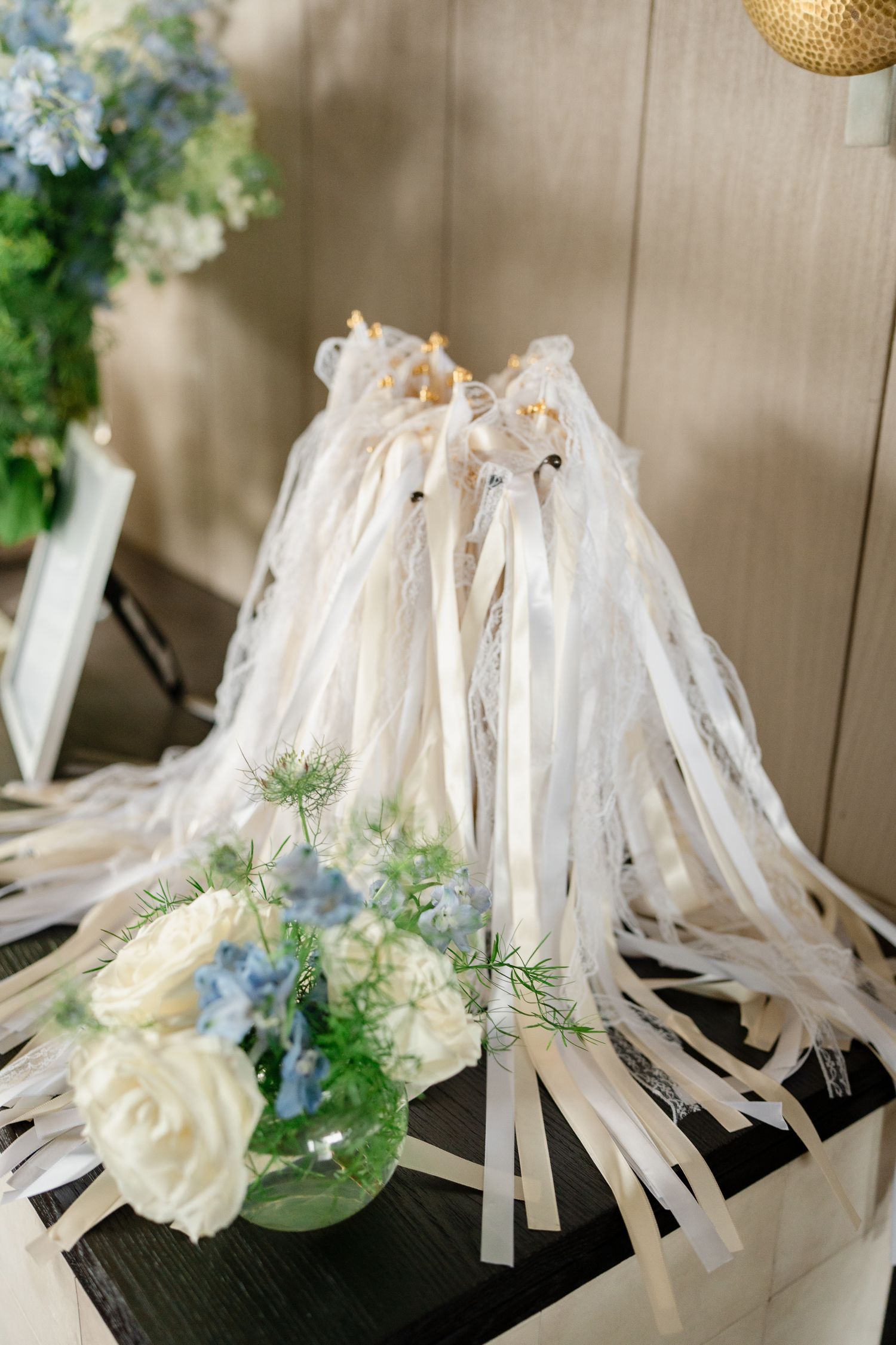 White ribbon wands decorated with blue and cream flowers for wedding ceremony send-off.