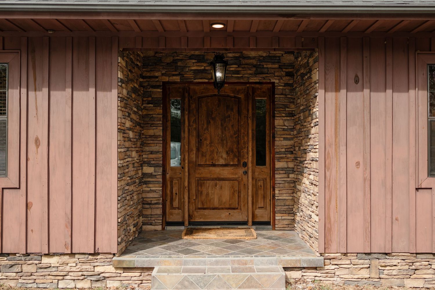 Rustic wooden barn entrance with stone accents and pink-tinted siding.