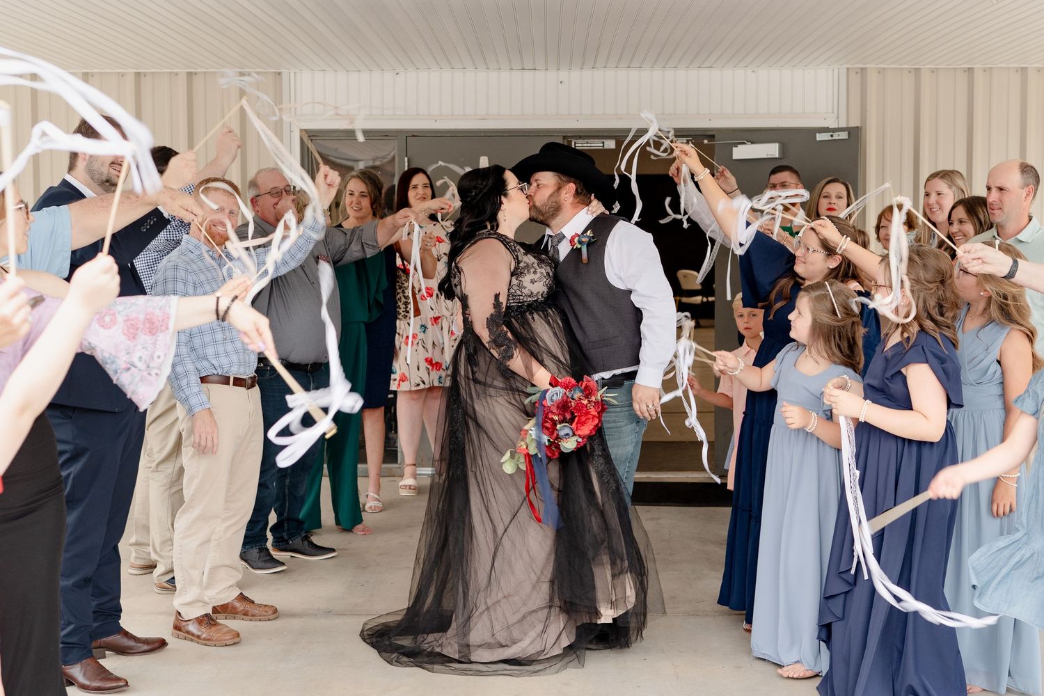 Wedding guests form a celebratory tunnel with raised arms as a couple walks through during a reception.