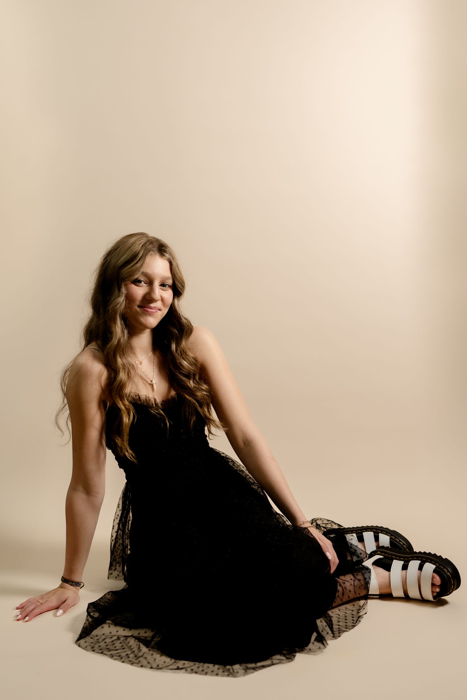 A black lace dress is showcased in a series of elegant floor poses against a light background.