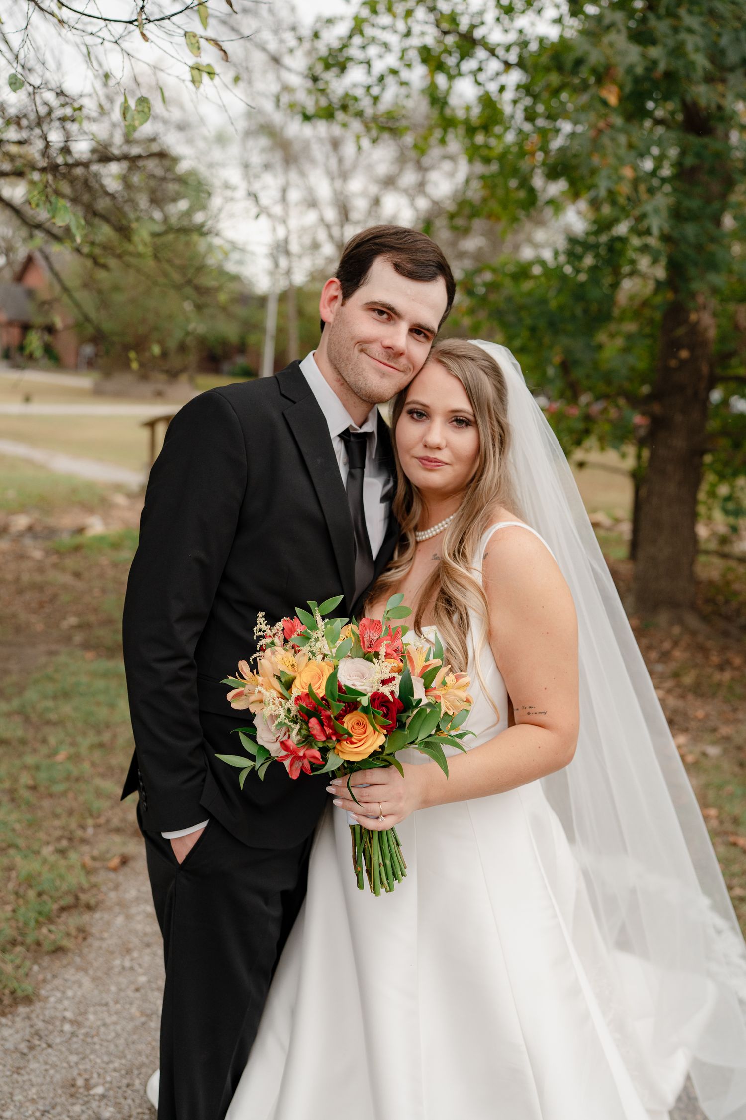 A bride and groom share intimate moments in a series of outdoor wedding portraits with autumn florals.