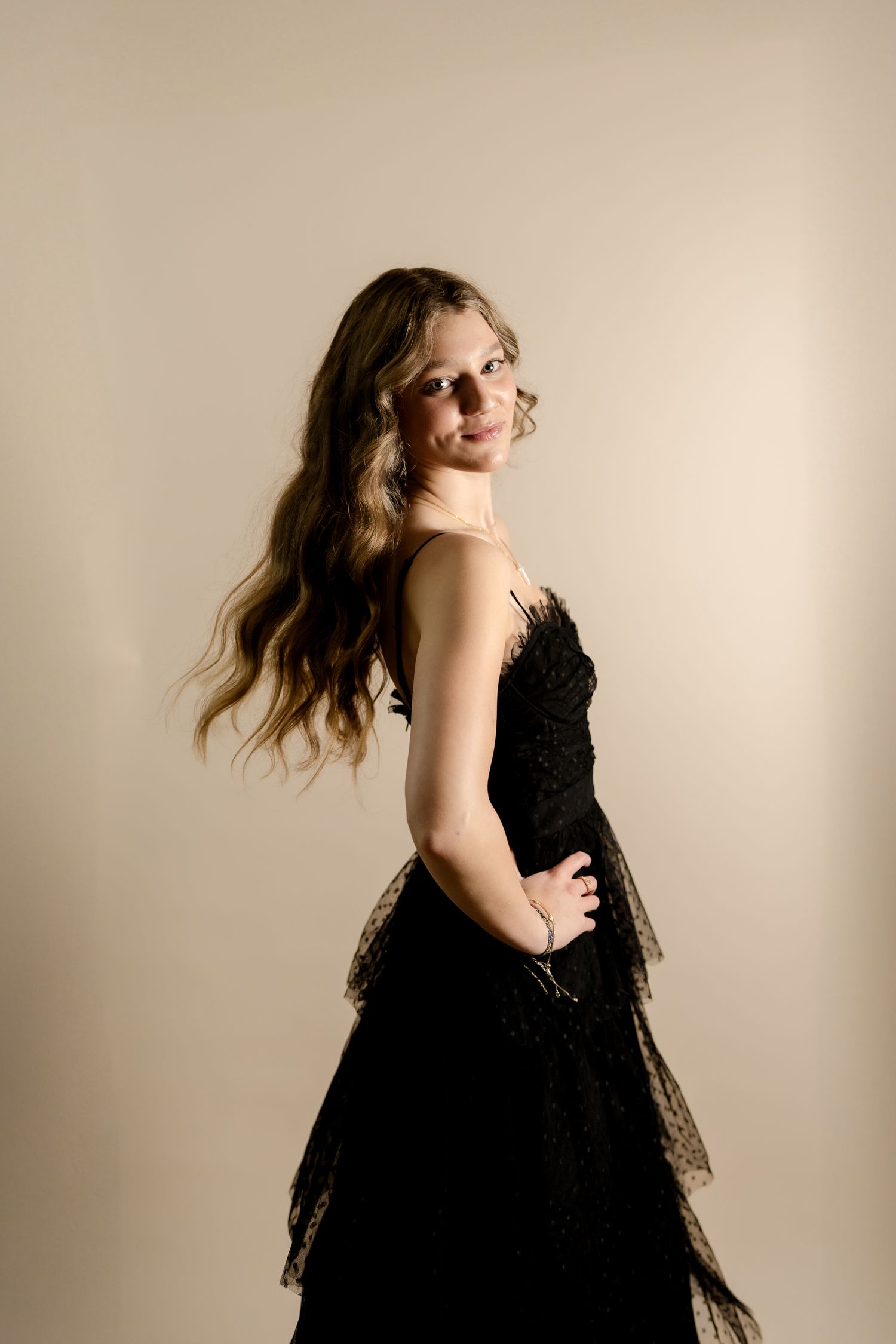 A black lace dress is photographed against a beige backdrop in an artistic fashion portrait series.