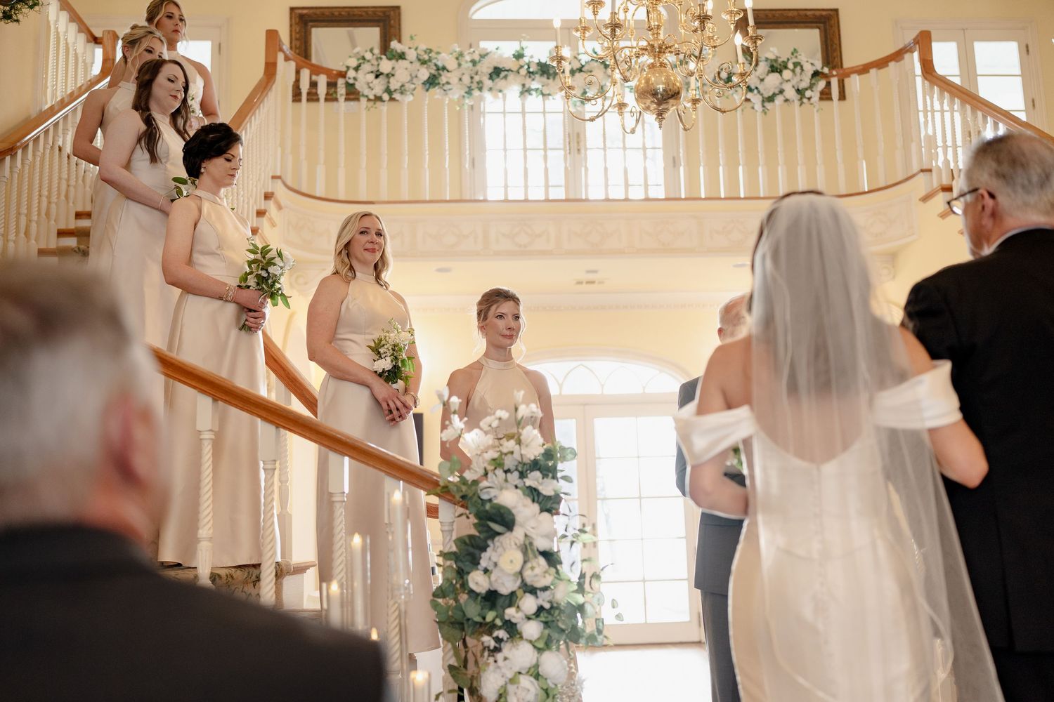 Wedding ceremony in an elegant venue with guests positioned along a curved staircase.