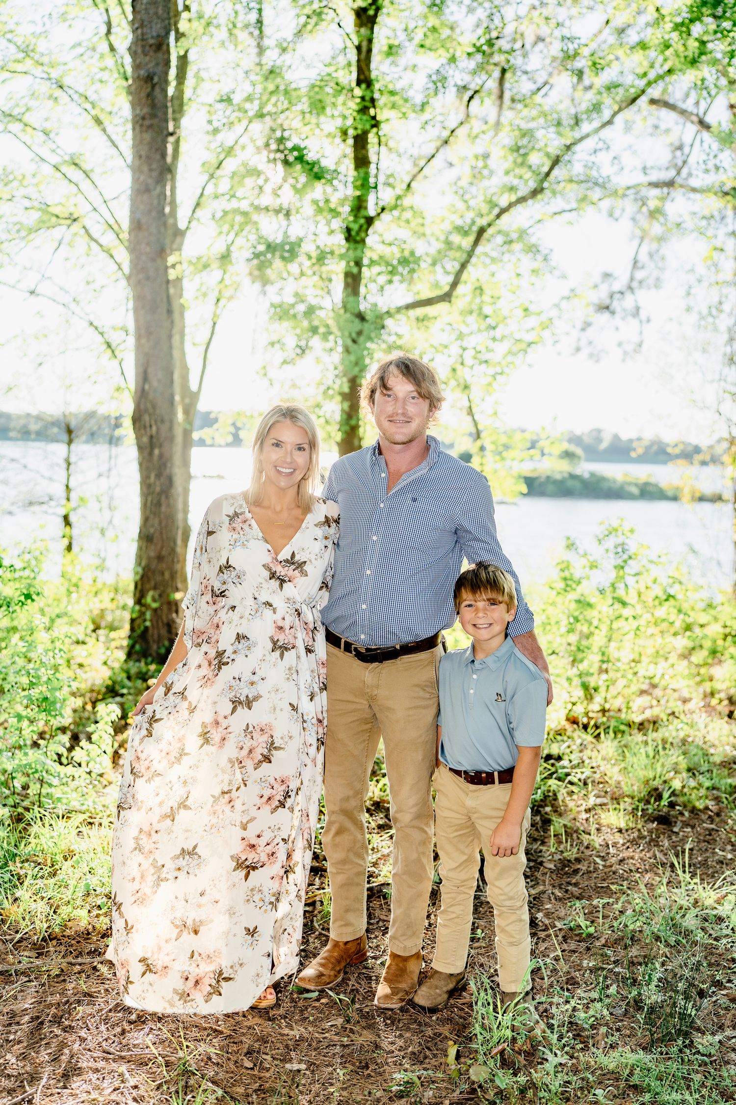 Family portrait session in a scenic wooded area near water with natural lighting.