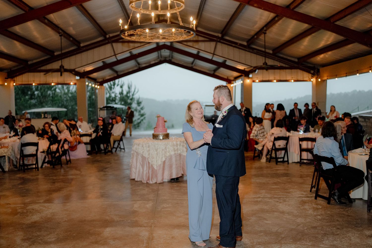 Couple shares a first dance under a elegant pavilion during their wedding reception with guests seated nearby.