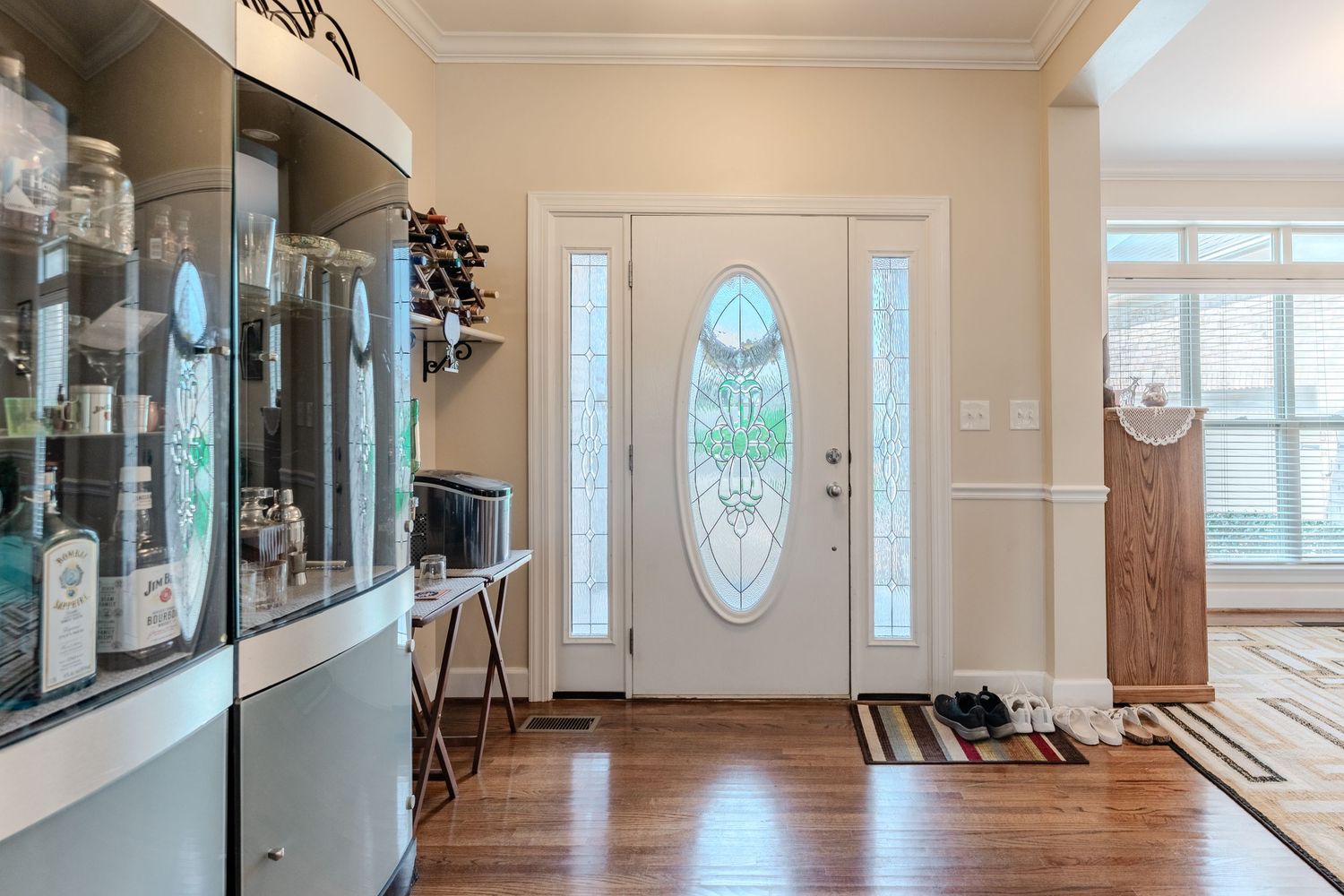 Interior panoramic view of an elegant white living room with hardwood floors and large windows letting in natural light.