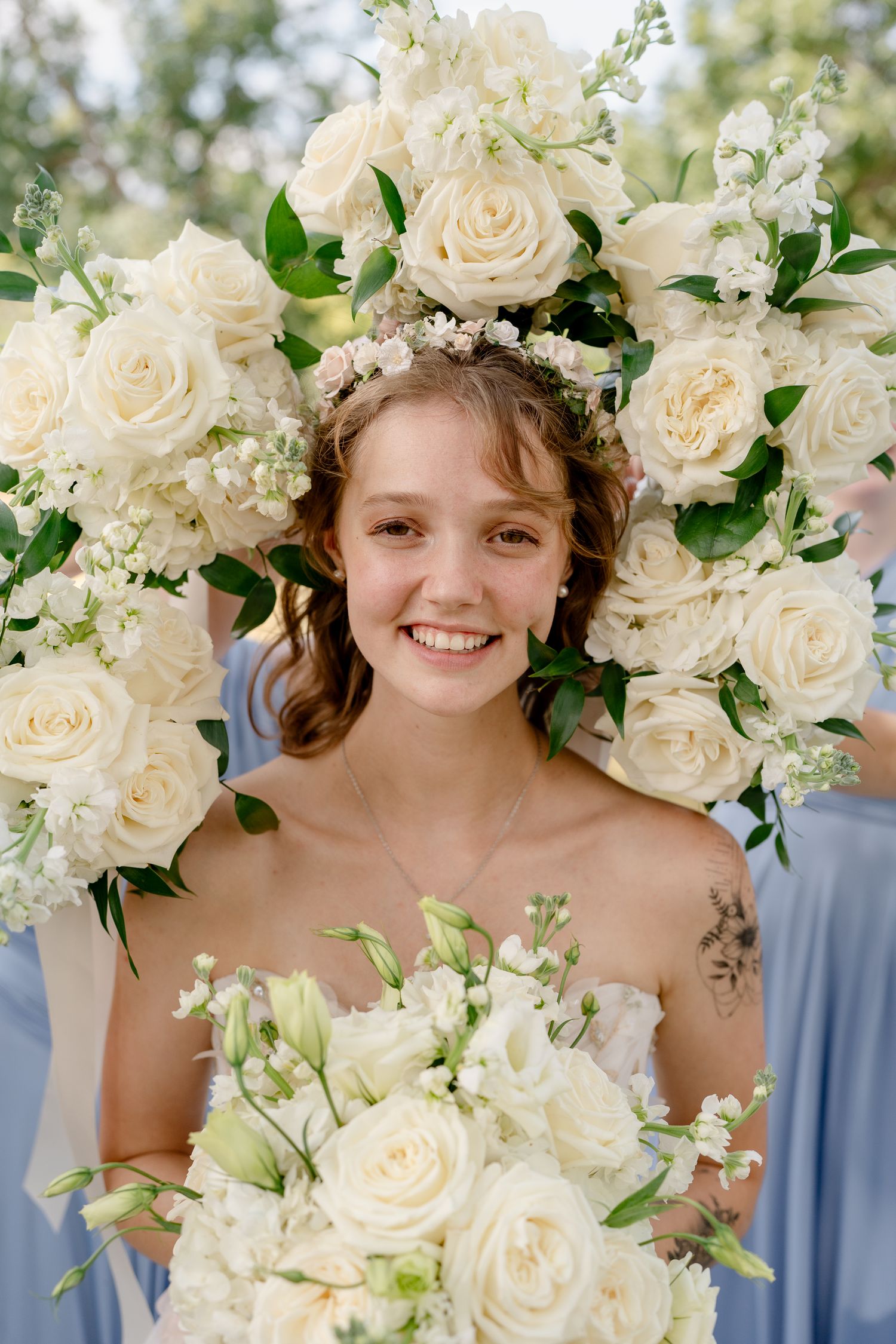 White roses and floral arrangements frame a joyful wedding celebration moment outdoors.