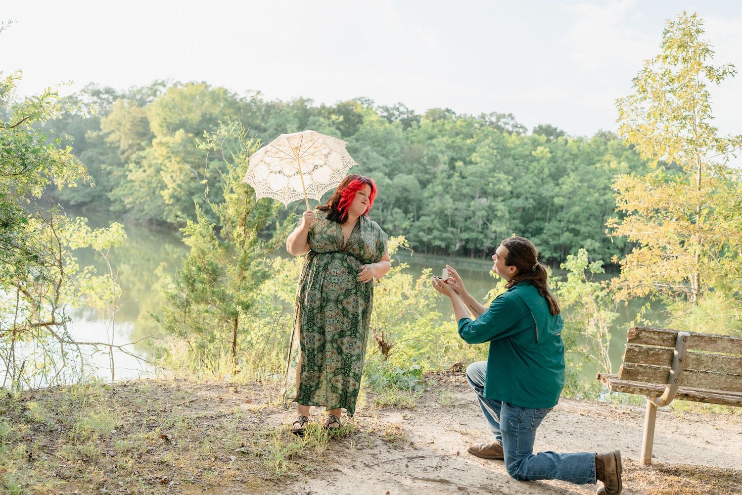 A couple shares a romantic moment on a scenic overlook with a lace parasol during golden hour.