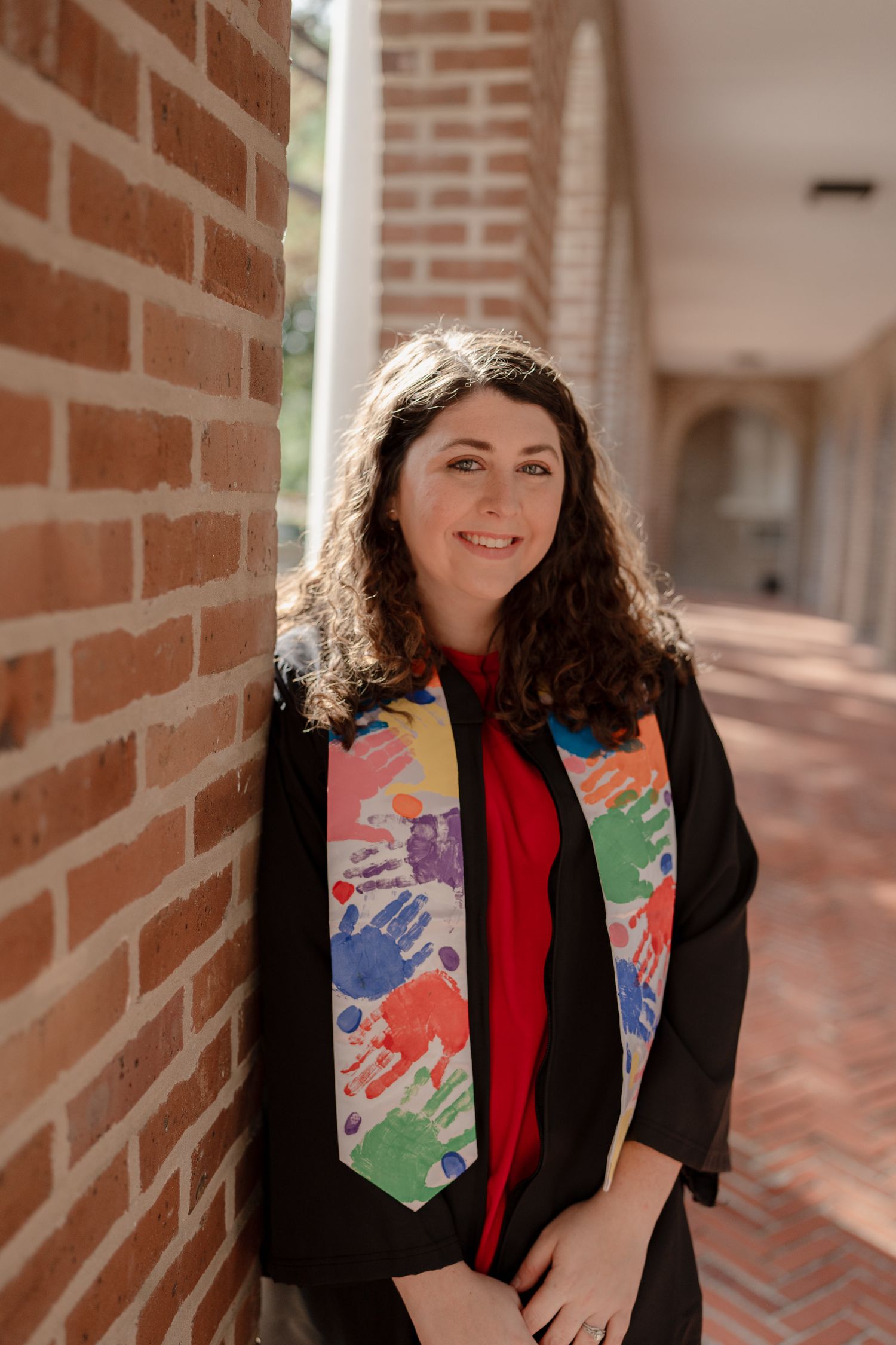 A series of four photos showing someone in a black blazer and colorful patterned tie posing against a brick wall.