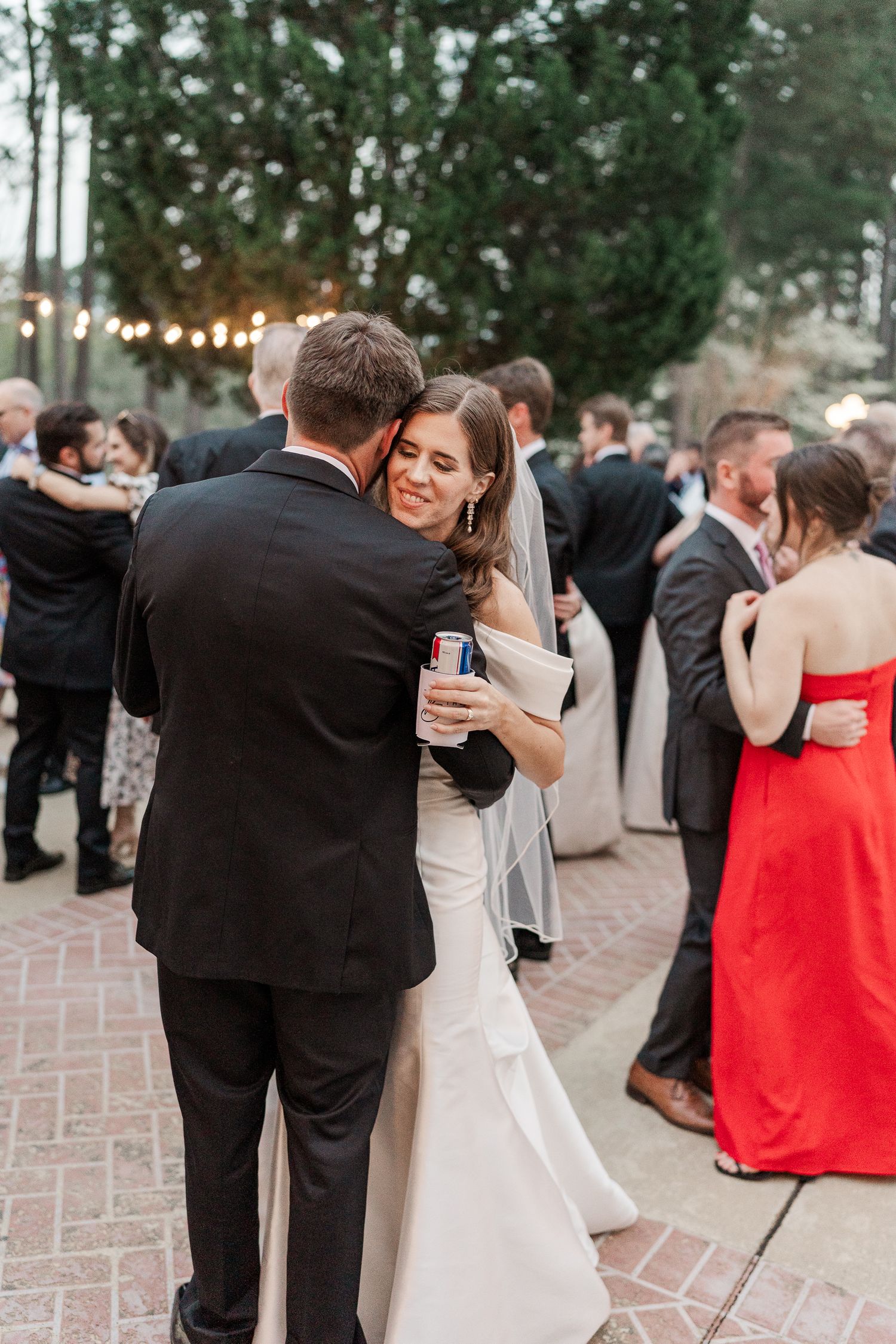 Couples dancing together at an outdoor wedding reception on a brick patio.
