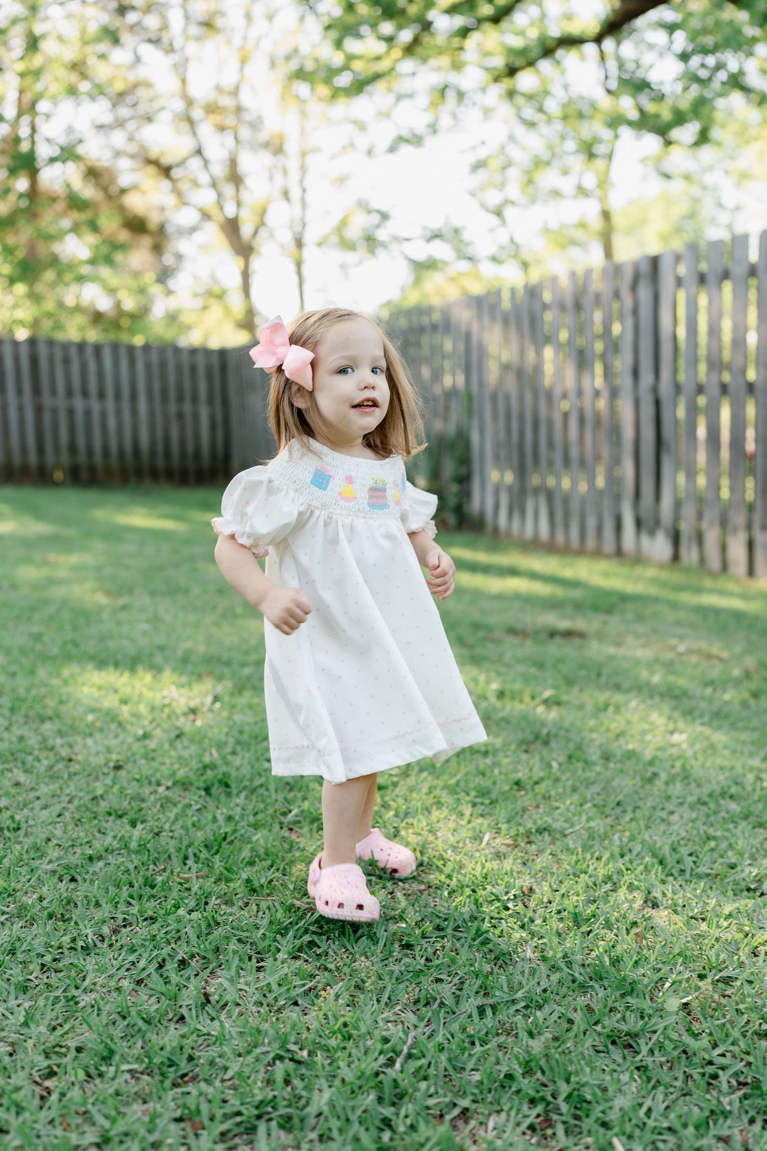Small figure in white dress runs joyfully across green grass.