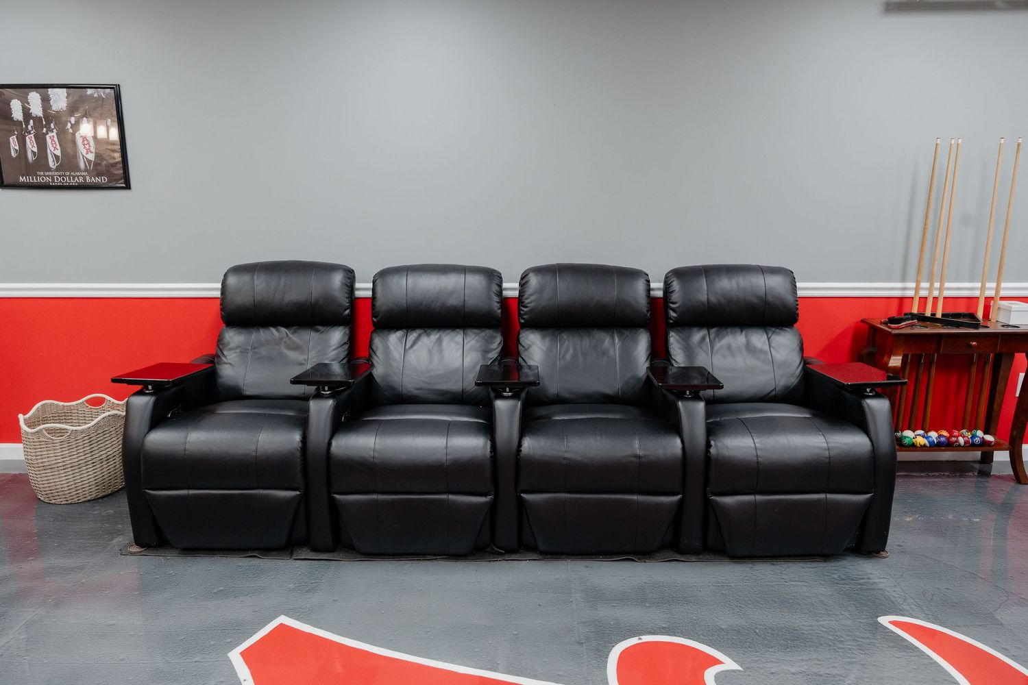 Contemporary media room featuring black leather recliners arranged in rows with red wall accents.