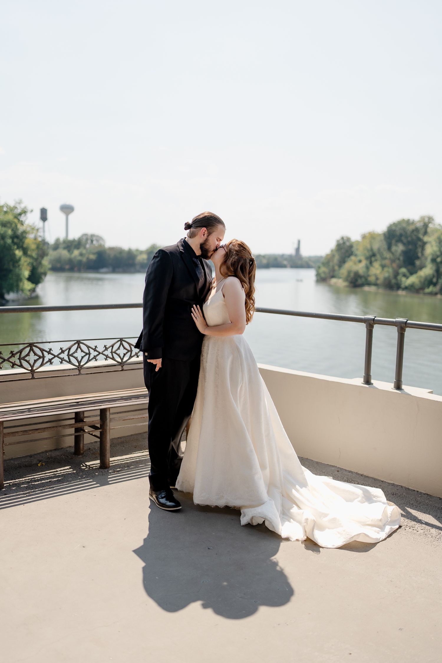 Romantic waterfront wedding photos with a couple on a balcony overlooking a scenic river view.