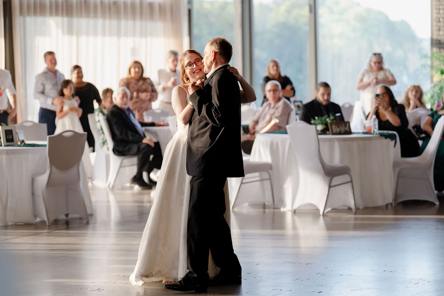 Couple shares their first dance at a wedding reception in a modern venue with panoramic views.
