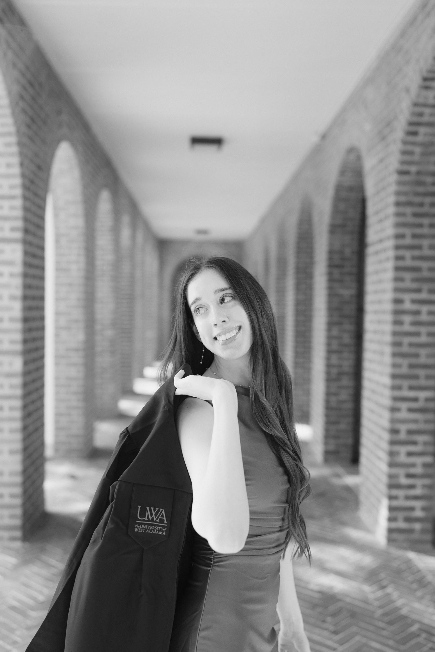 Four black and white portraits showing someone with long dark hair posing in an arched brick hallway.