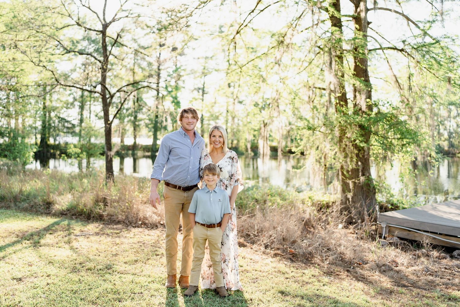 Natural light family portraits in wooded setting with golden sunlight filtering through trees.