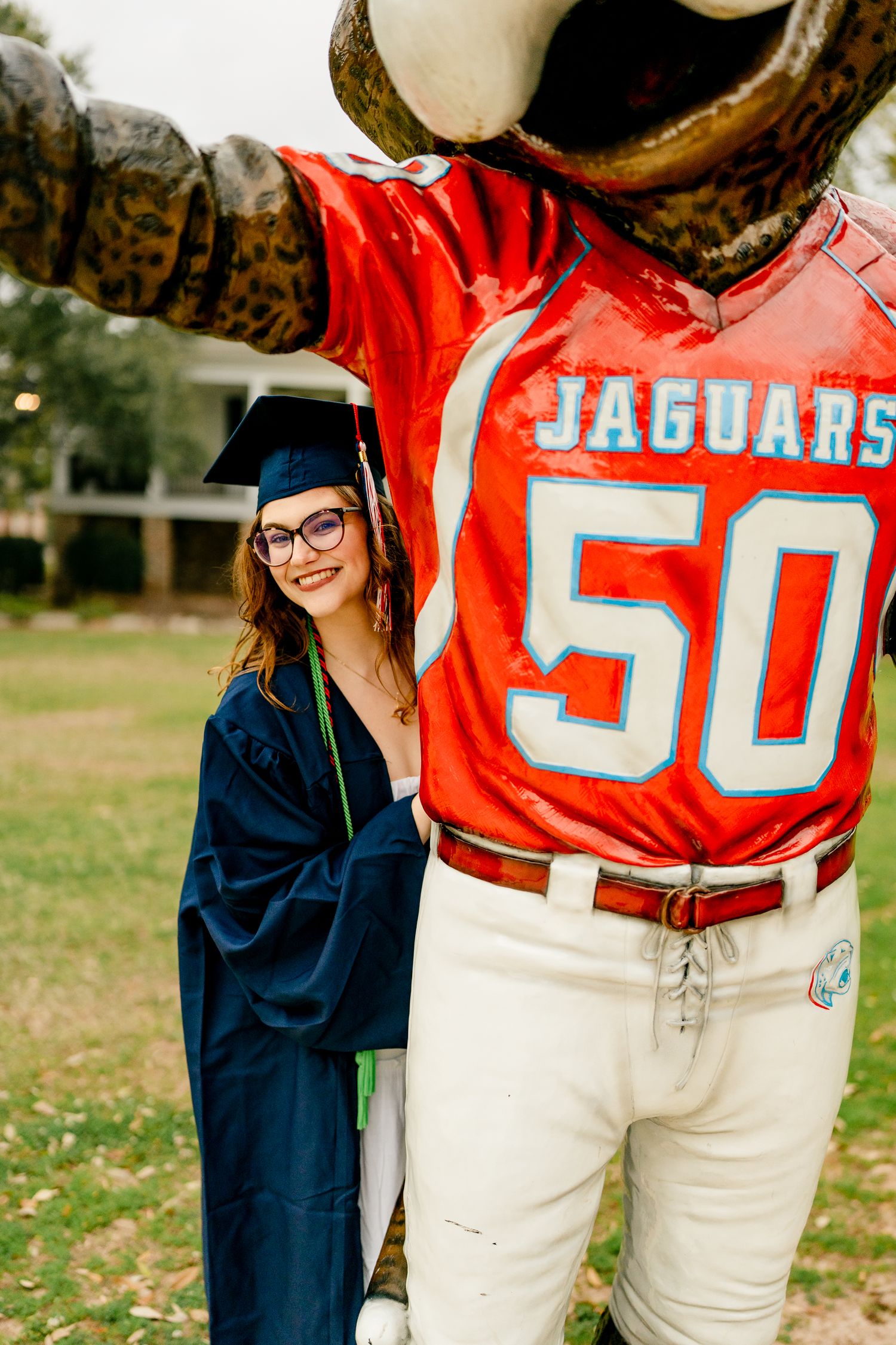 Graduate poses with Jaguars mascot jersey number 50 during outdoor graduation photo session.
