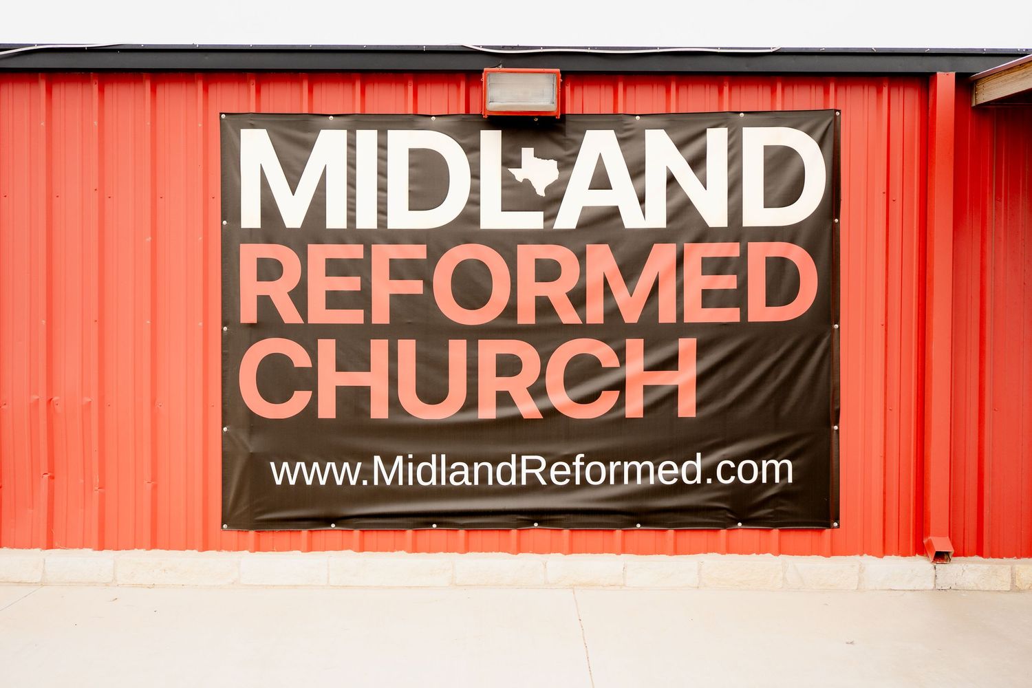 A red church building exterior with signage for Midland Reformed Church and website URL displayed.