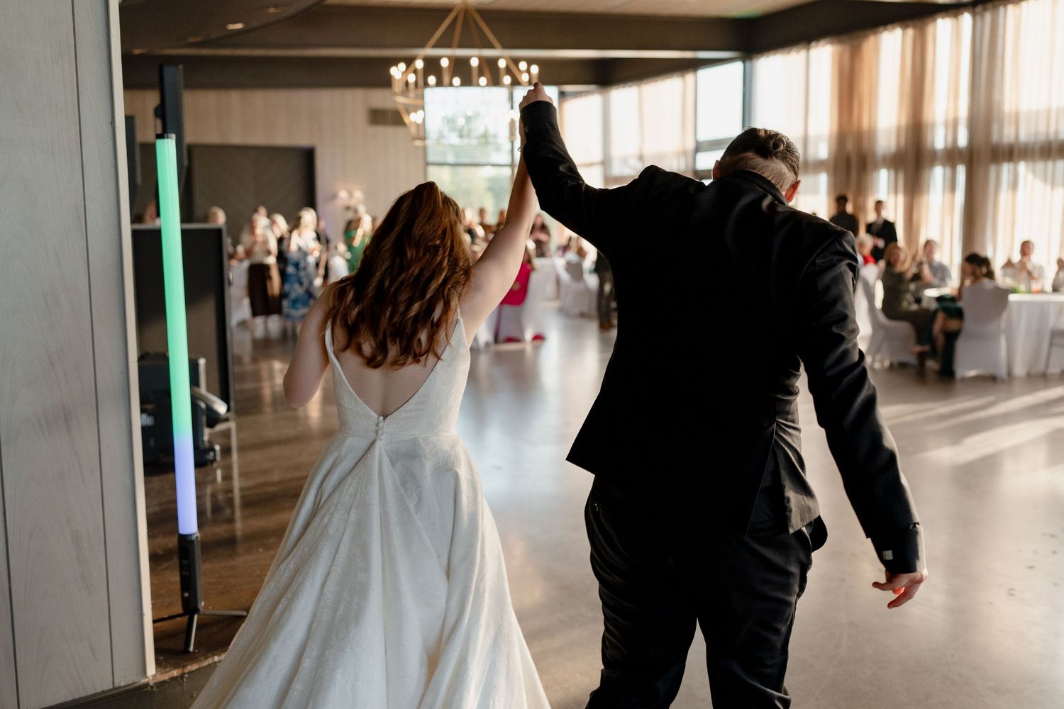 Wedding couple walks through modern airport terminal with luggage and wedding attire.